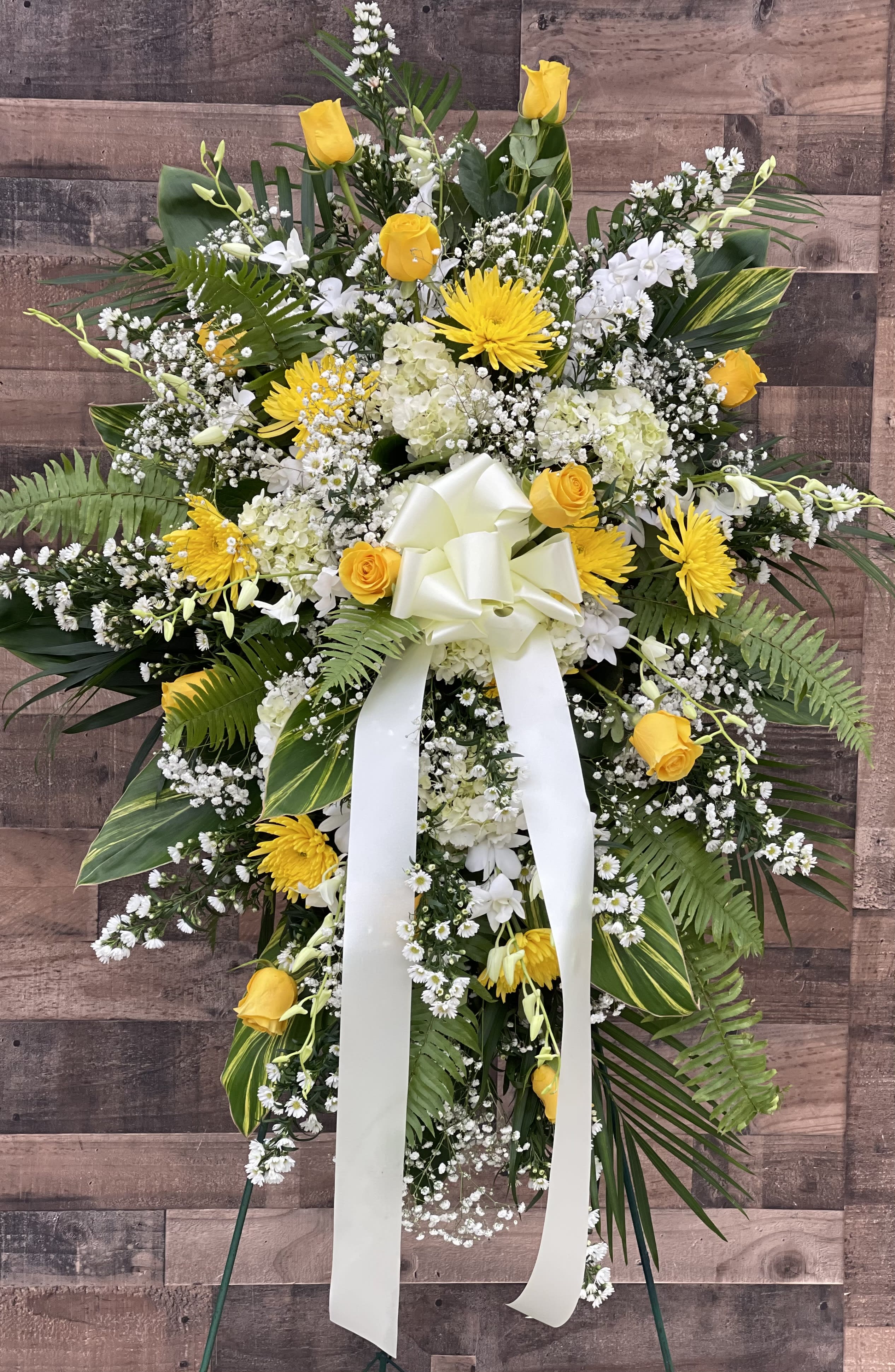 Standing floral spray with yellow roses, white blooms, and a white ribbon bow
