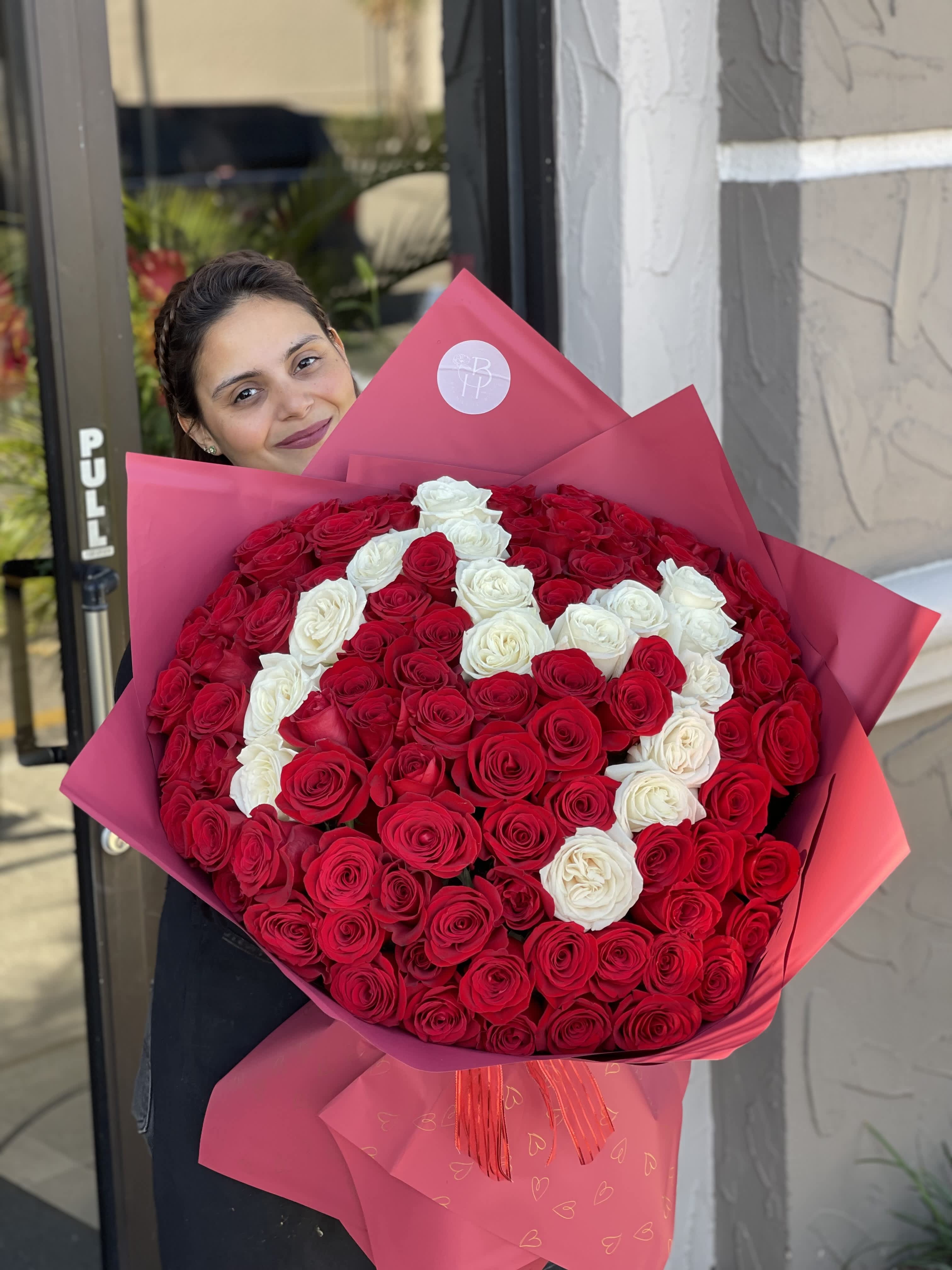 Large bouquet of red and white roses wrapped in pink paper