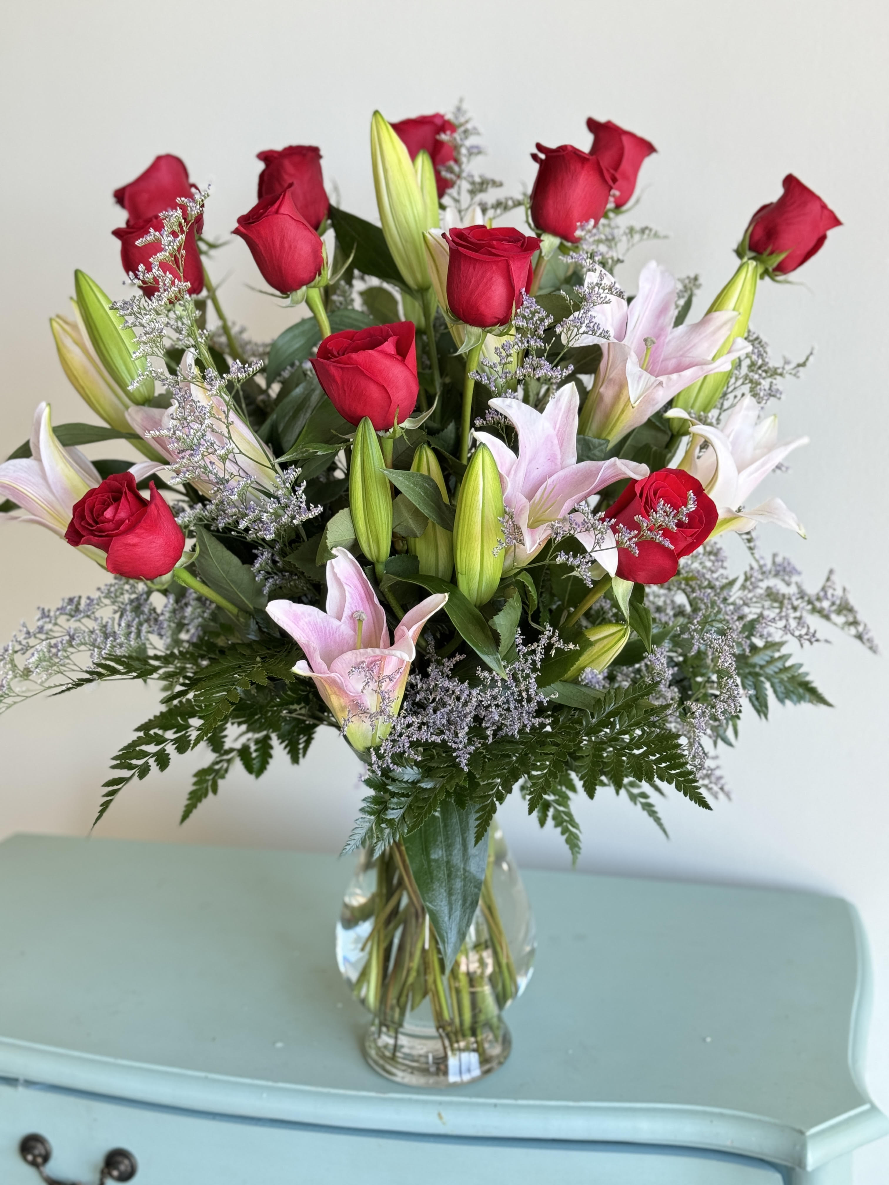 Bouquet of red roses and pink lilies in a clear glass vase