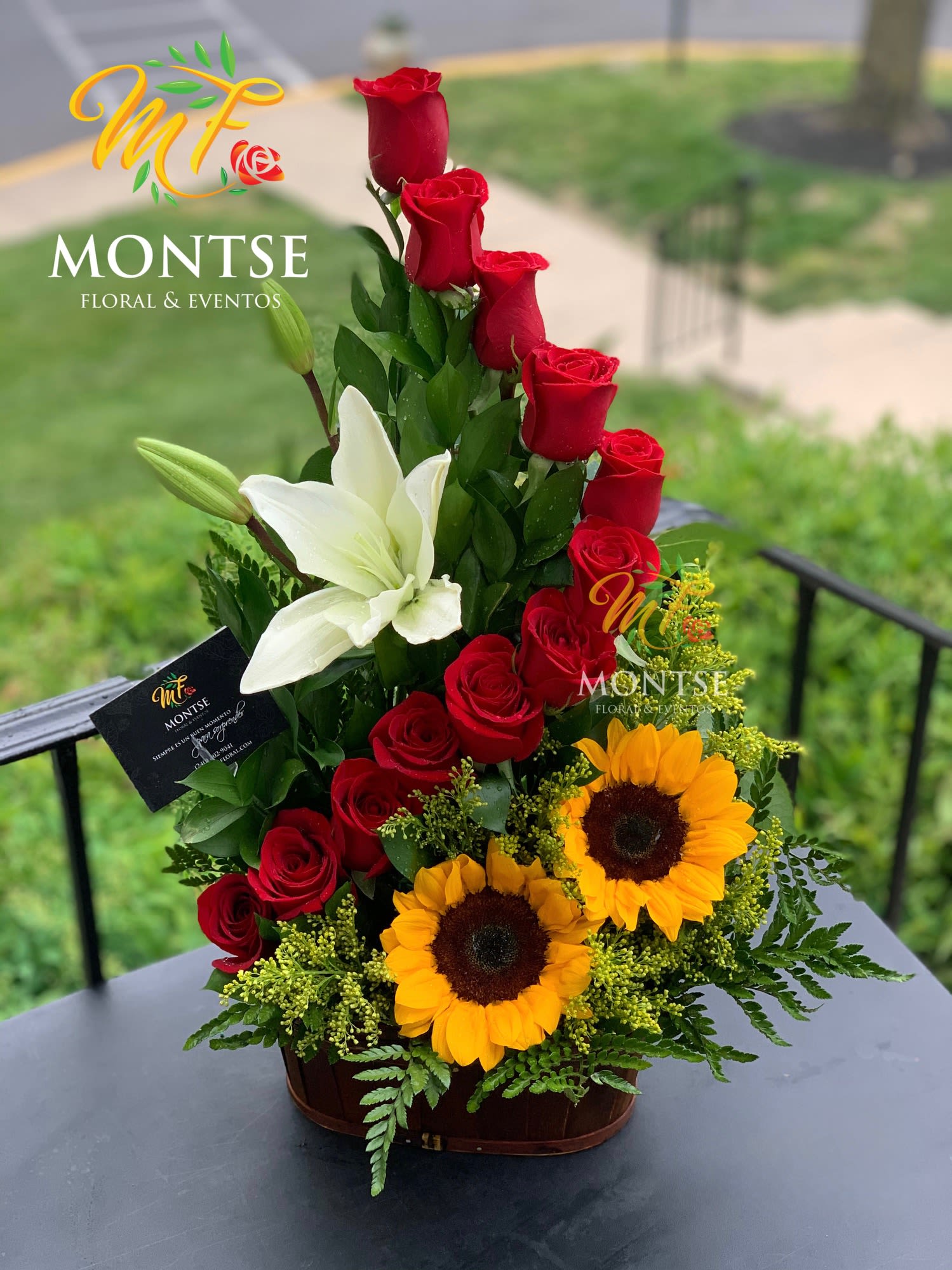 Tall arrangement of red roses, white lilies, and sunflowers in a basket
