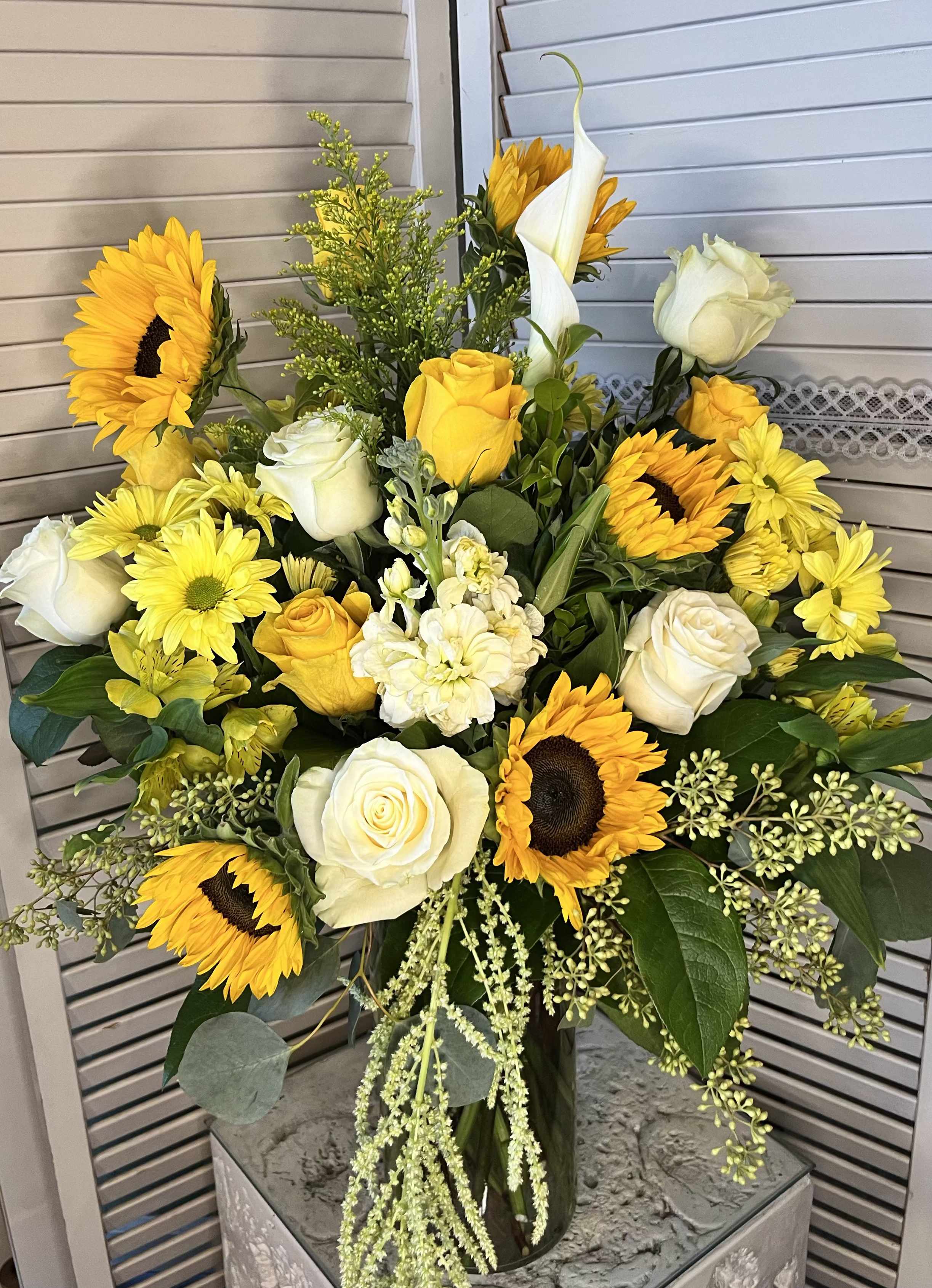 Bouquet of yellow sunflowers and white roses in a glass vase