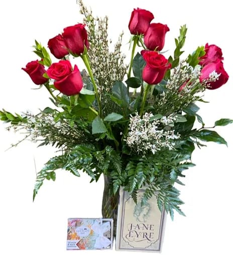 Red roses in a glass vase with greenery and a greeting card