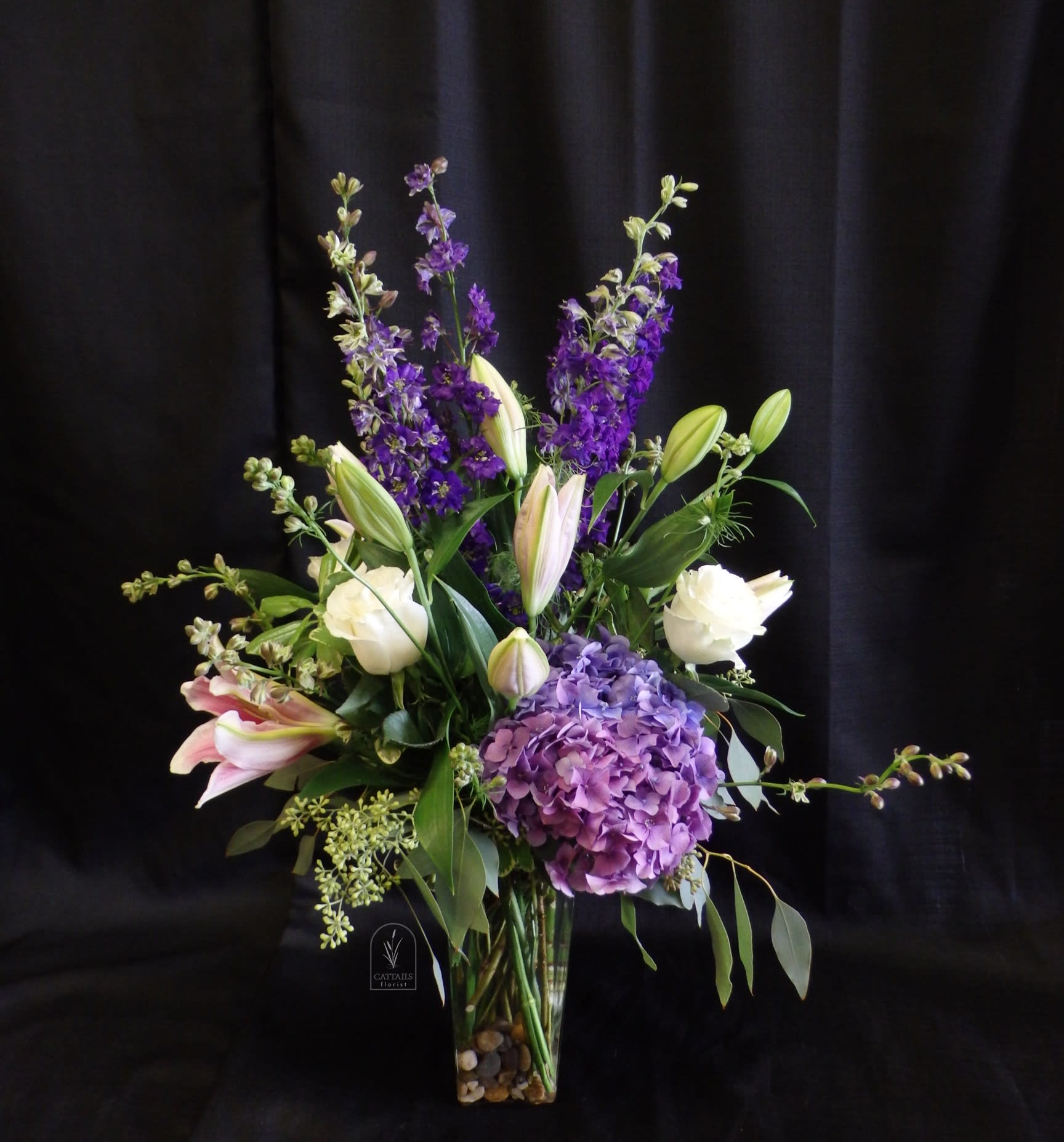 Purple and white floral arrangement in a clear glass vase