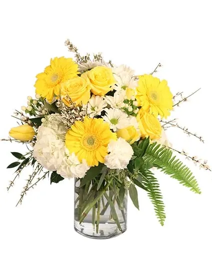 Yellow and white flowers arranged in a clear glass vase