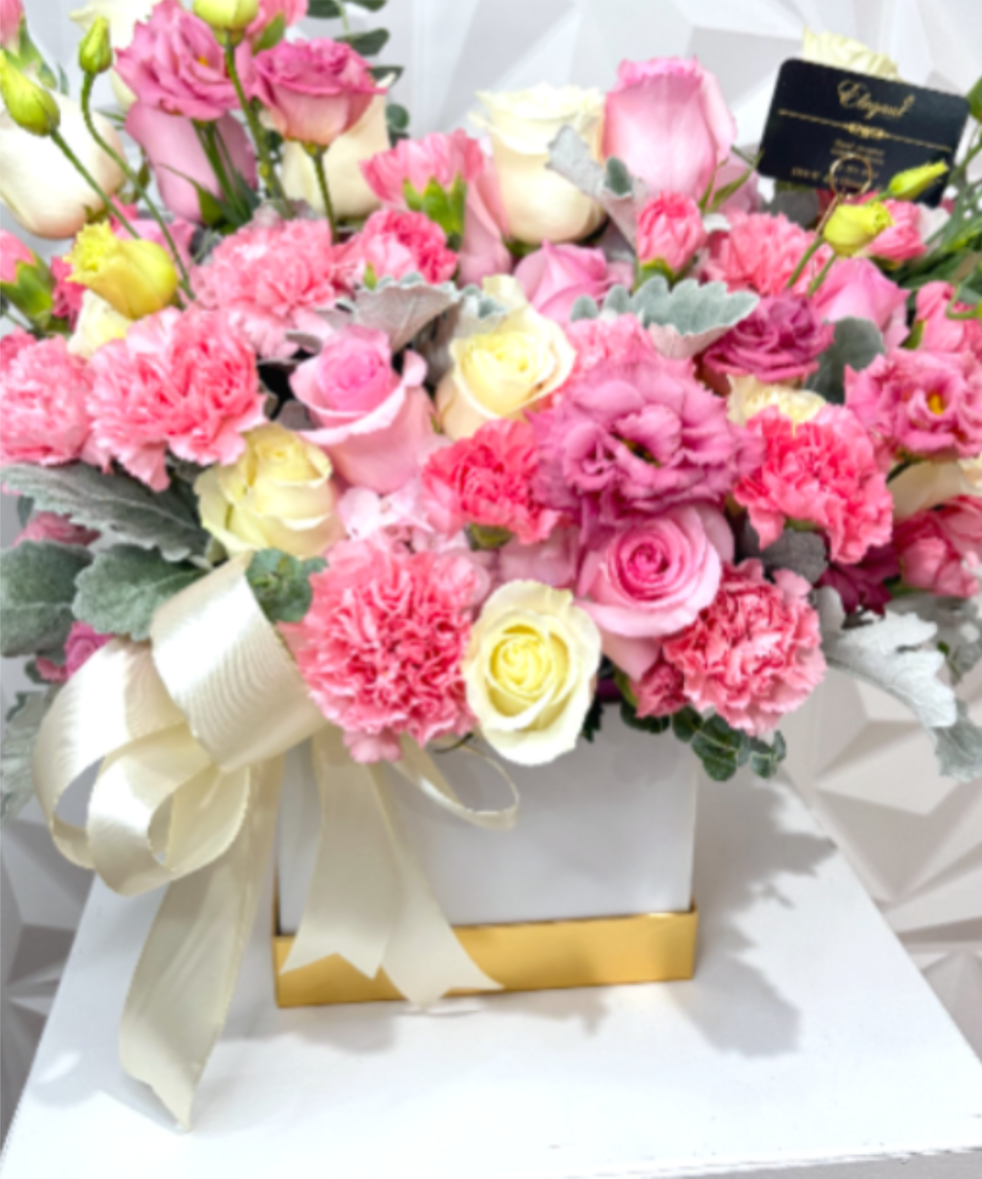 Elegant Pink Blush collection - A luxurious floral arrangement designed in a modern white box, featuring a delicate blend of soft pink and white blooms. This elegant design includes premium pink roses, white roses, blush pink lisianthus, and pink carnations, beautifully accented with soft silver-gray dusty miller foliage