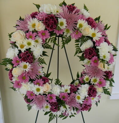 Pink and white floral wreath on a black easel