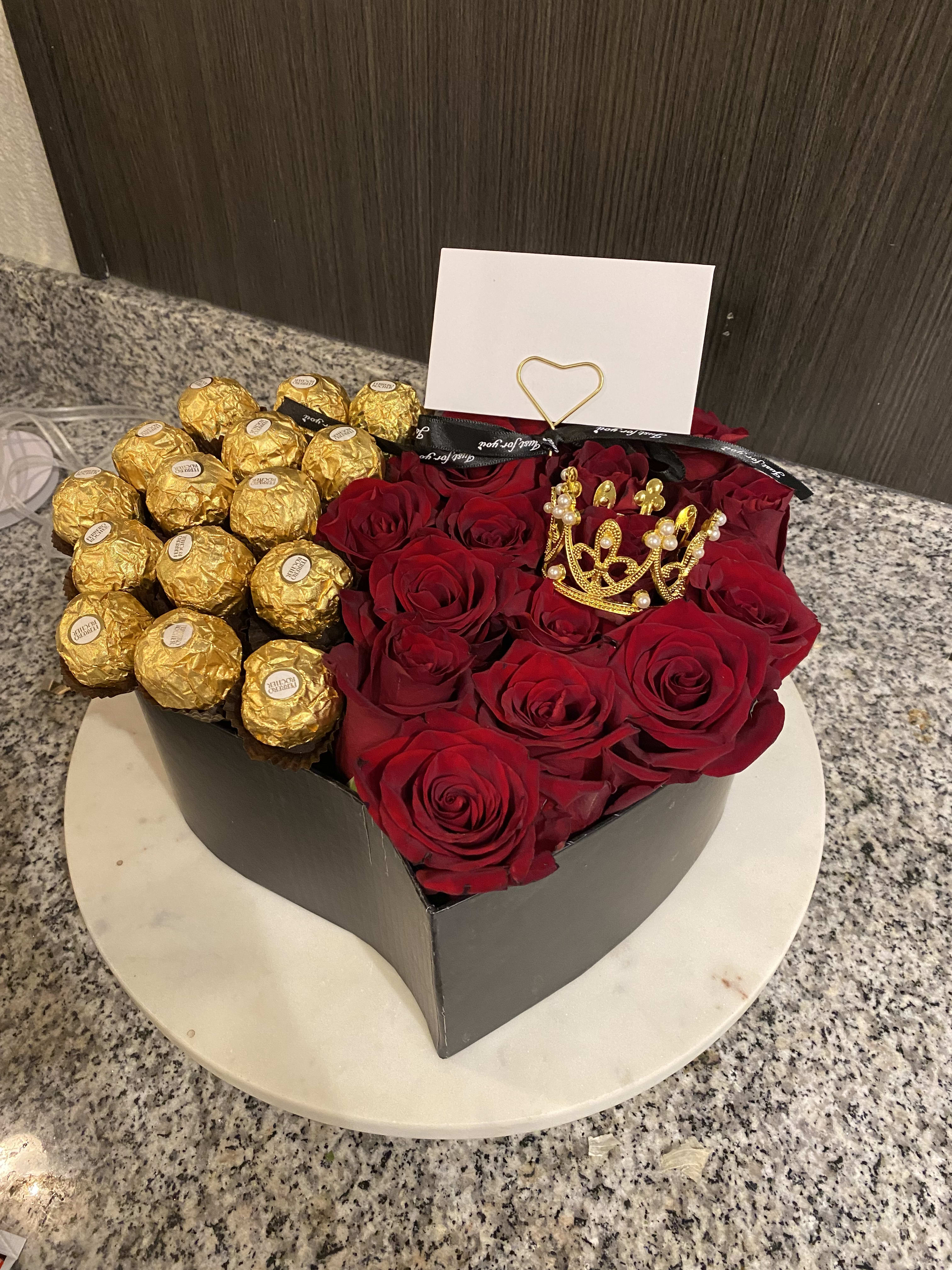 Heart-shaped box of red roses and gold-wrapped chocolates with a card.
