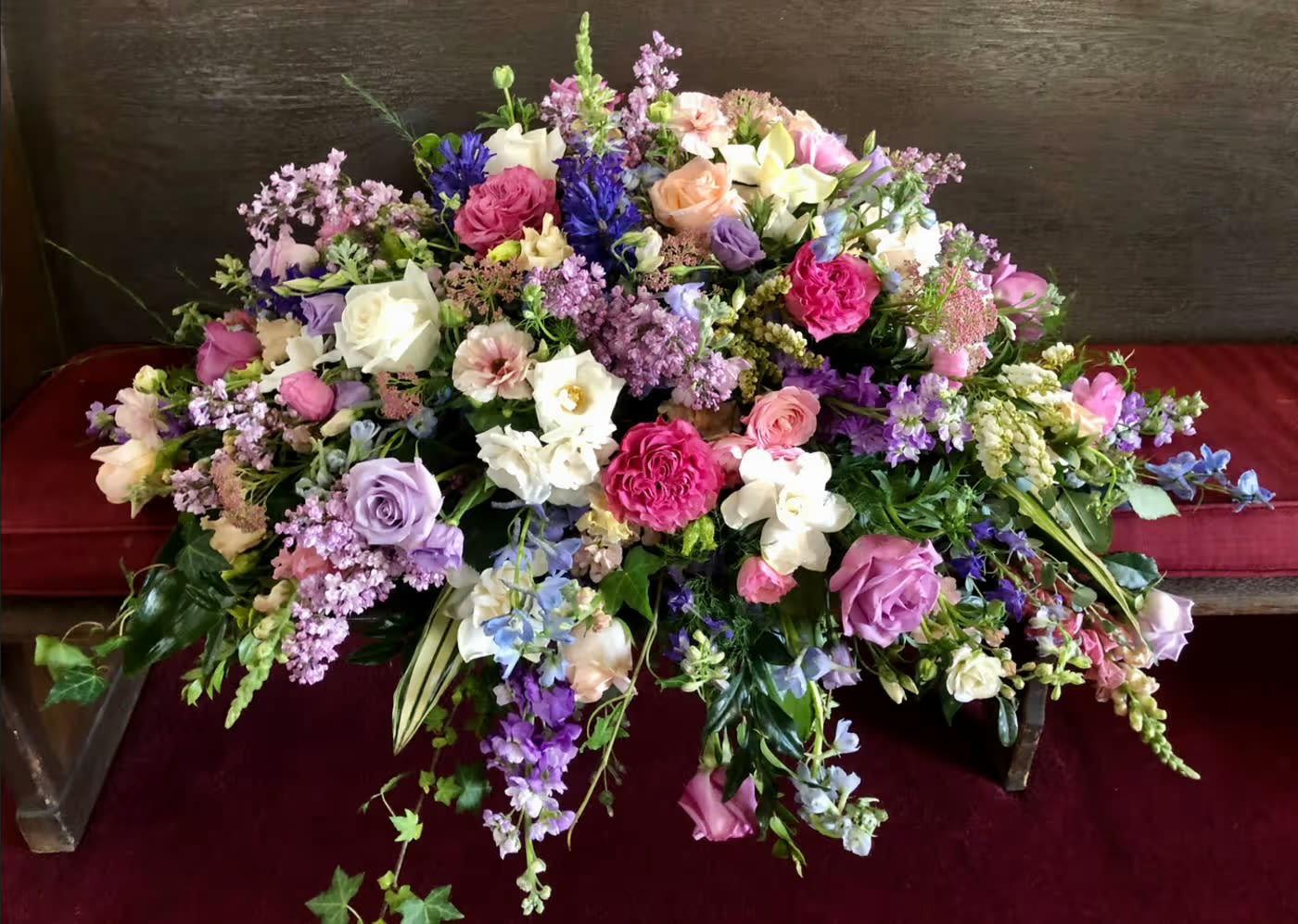Large mixed floral arrangement with roses, orchids, and lilac blooms
