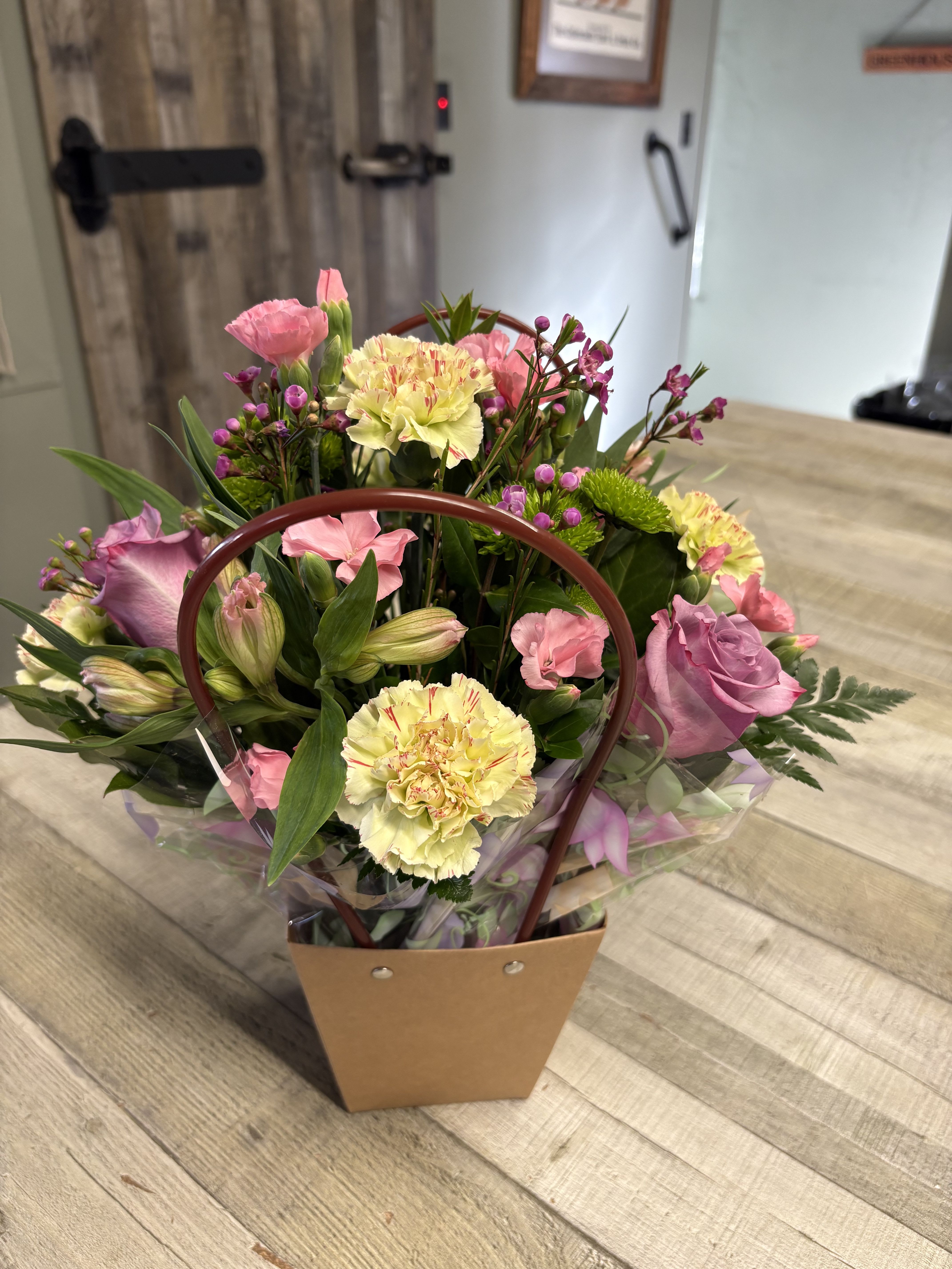 Mixed pink and yellow bouquet in a handled gift bag