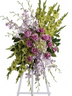 Standing floral spray with purple roses and green orchids on an easel