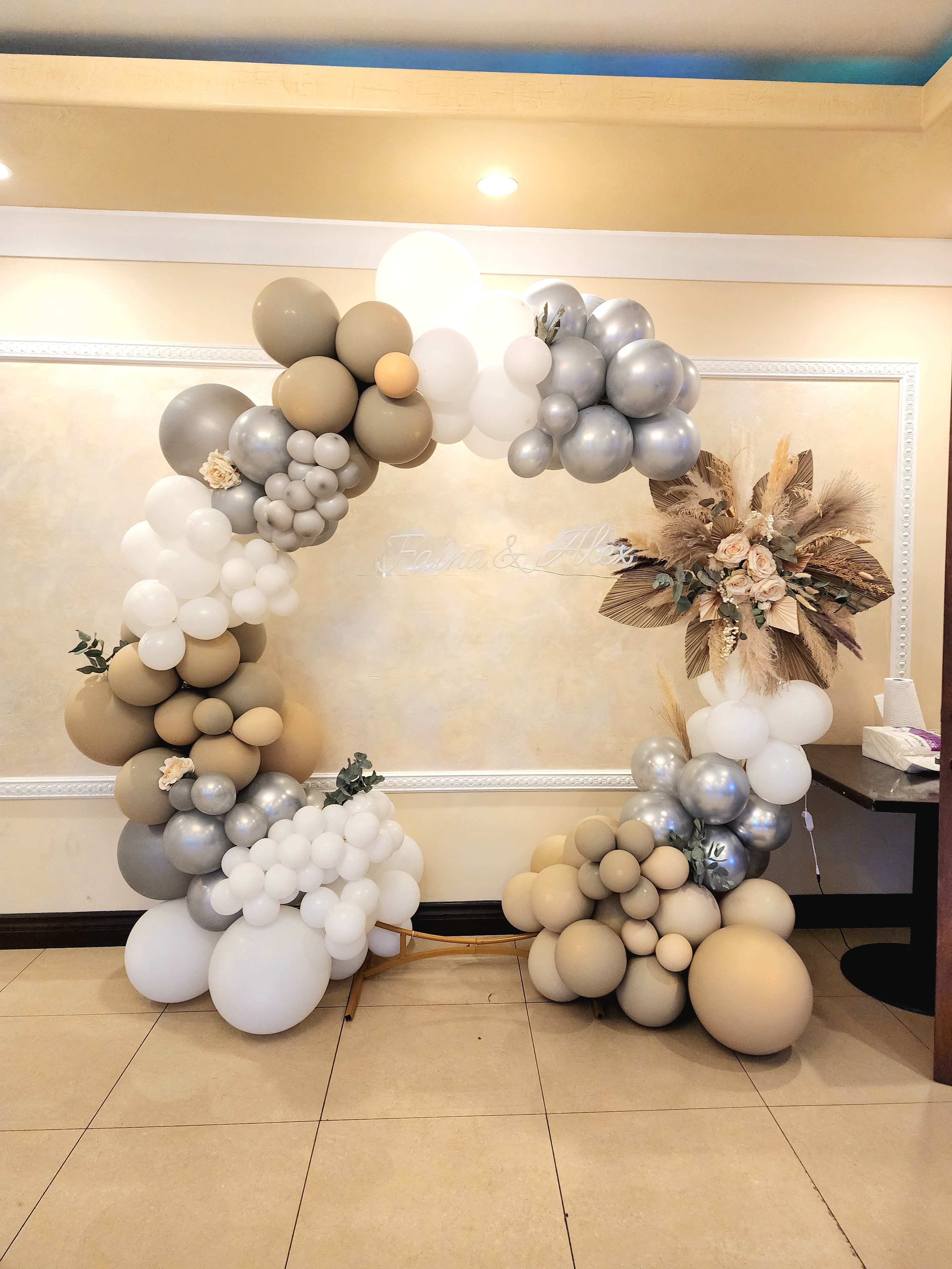 Balloon arch in beige, white, and silver with dried floral accents