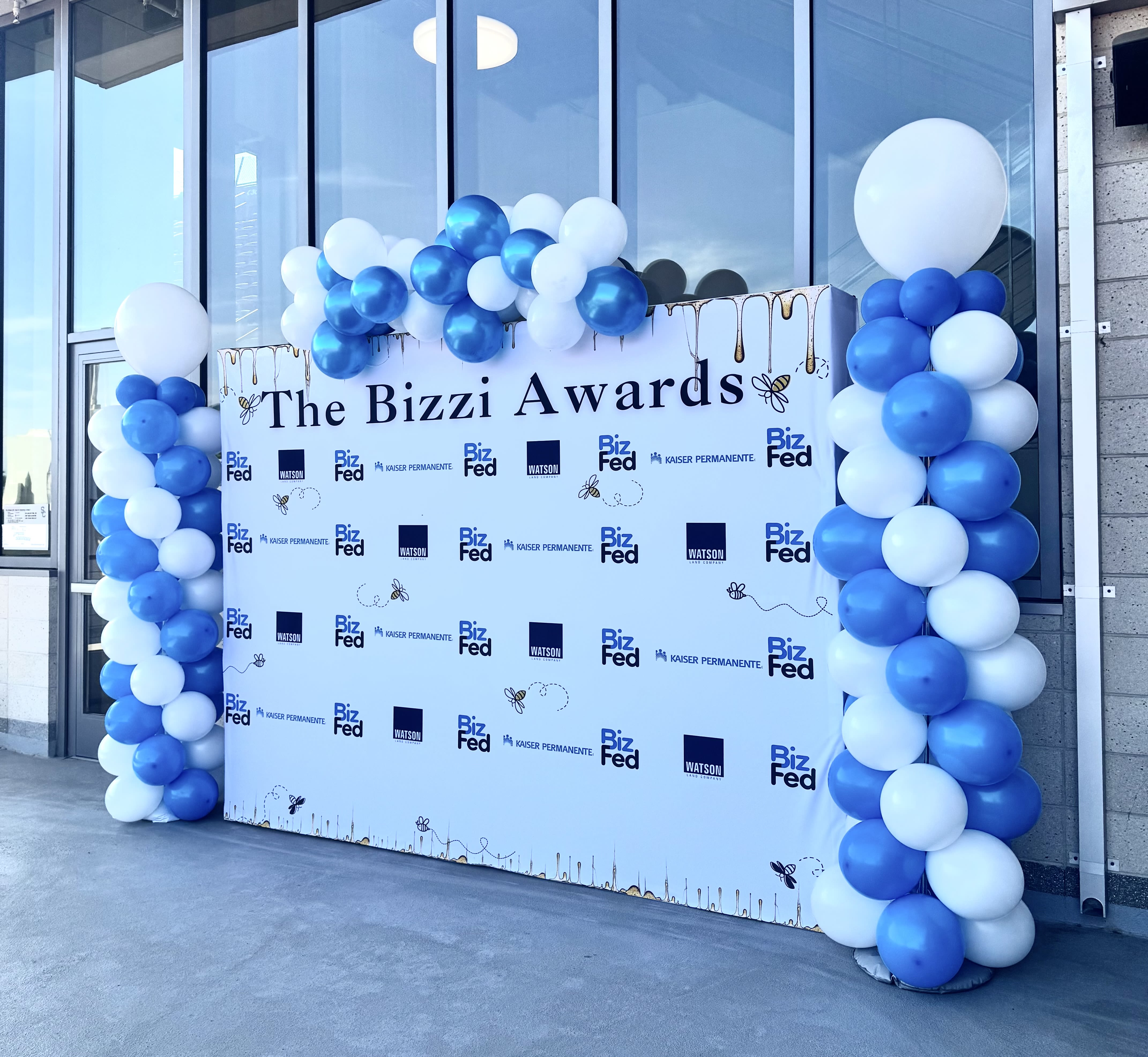 Blue and white balloon columns framing a Bizzi Awards backdrop