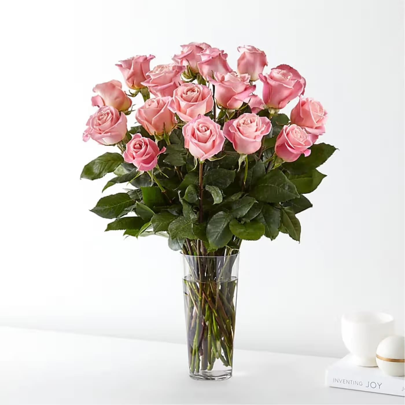 2 Dozen Pink Roses - Dive into a moment of gentle romance with Flower Synergy’s elegant pink rose arrangement, featuring two dozen premium pink roses designed to express affection with grace and sincerity. Arranged in a clear glass vase, these delicate blooms showcase soft blush tones and velvety petals, creating a look that is both timeless and heartfelt.  Each premium pink rose is carefully selected for its beauty and longevity, symbolizing admiration, gratitude, and tender emotion. The clear vase allows the roses to take center stage, highlighting their natural elegance and creating a light, airy presentation that feels effortlessly romantic.  Designed by the floral artisans at Flower Synergy, this arrangement is a beautiful way to celebrate love, appreciation, or meaningful moments. Order online or visit us in-store and let our professional delivery service ensure your flowers arrive fresh, perfectly arranged, and ready to bring a touch of pink elegance to any space.