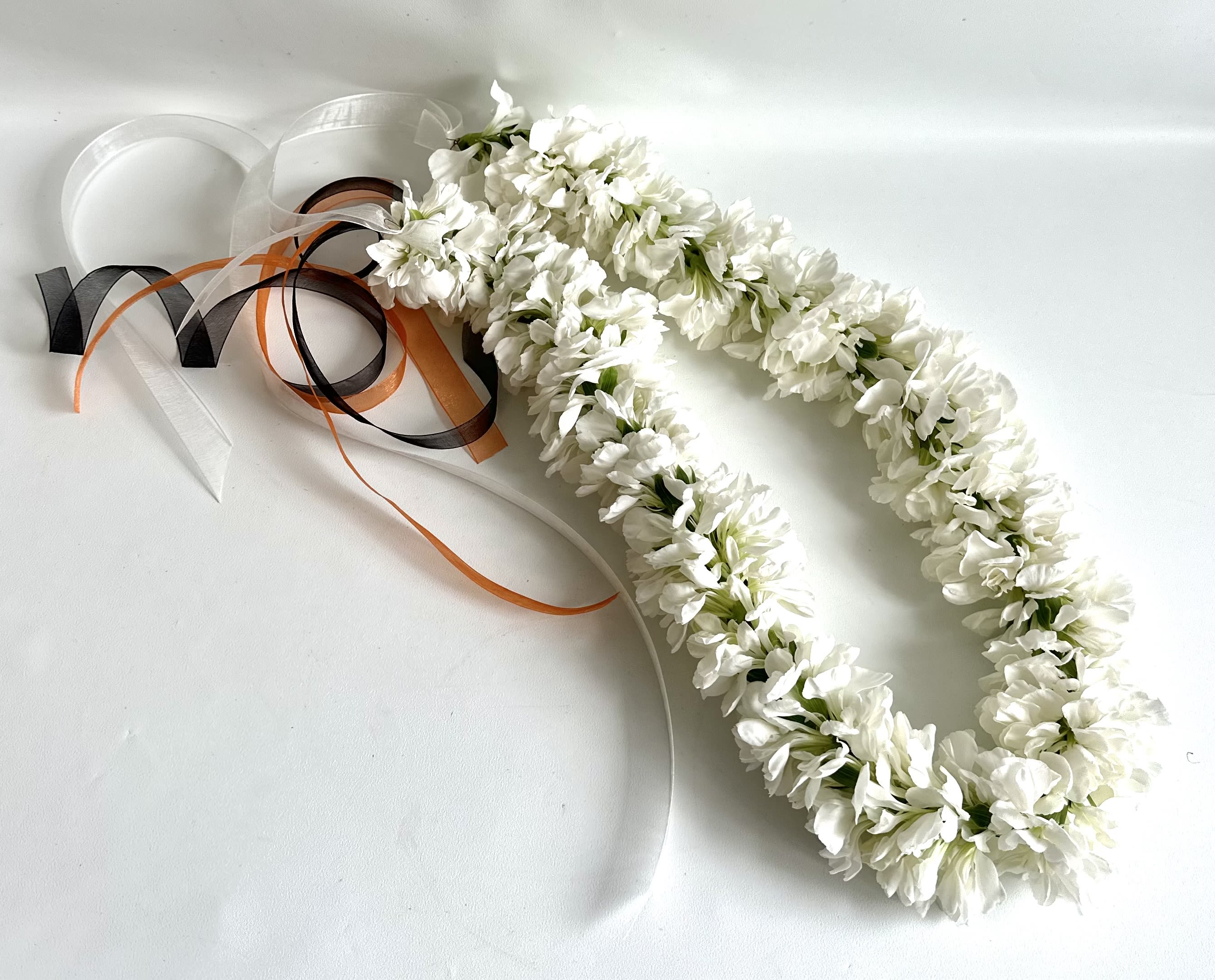 White floral lei with black, orange, and white ribbons