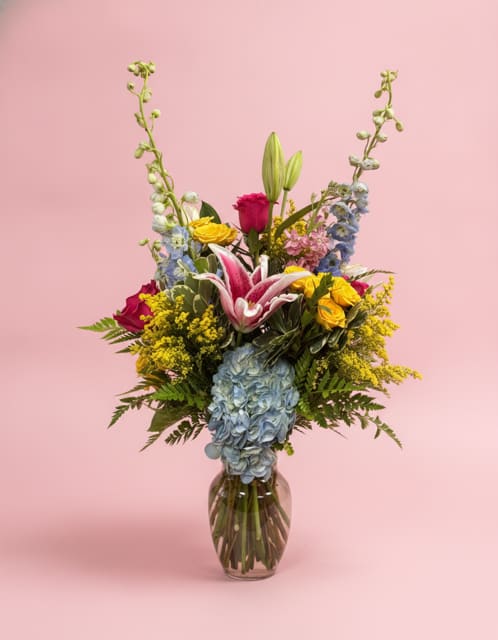 Best Friend - Just like a true best friend, this vibrant garden-inspired arrangement brings joy, warmth, and beauty into every moment. Featuring luxurious hot pink roses and fragrant stargazer lilies, "Best Friend" is designed with a cheerful blend of blue, pink, and yellow blooms that create a lush, freshly gathered garden feel.