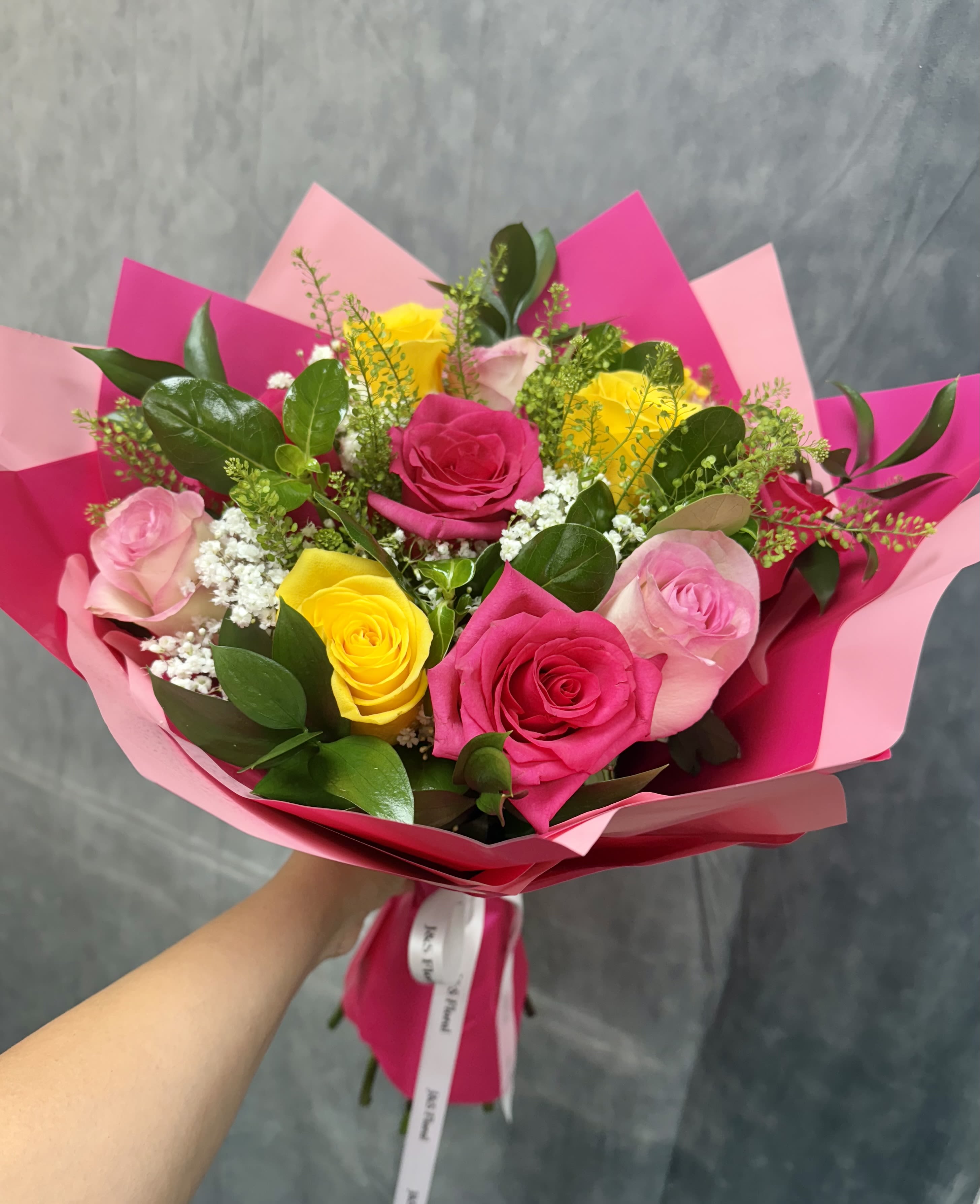 Bouquet of pink and yellow roses wrapped in bright pink paper