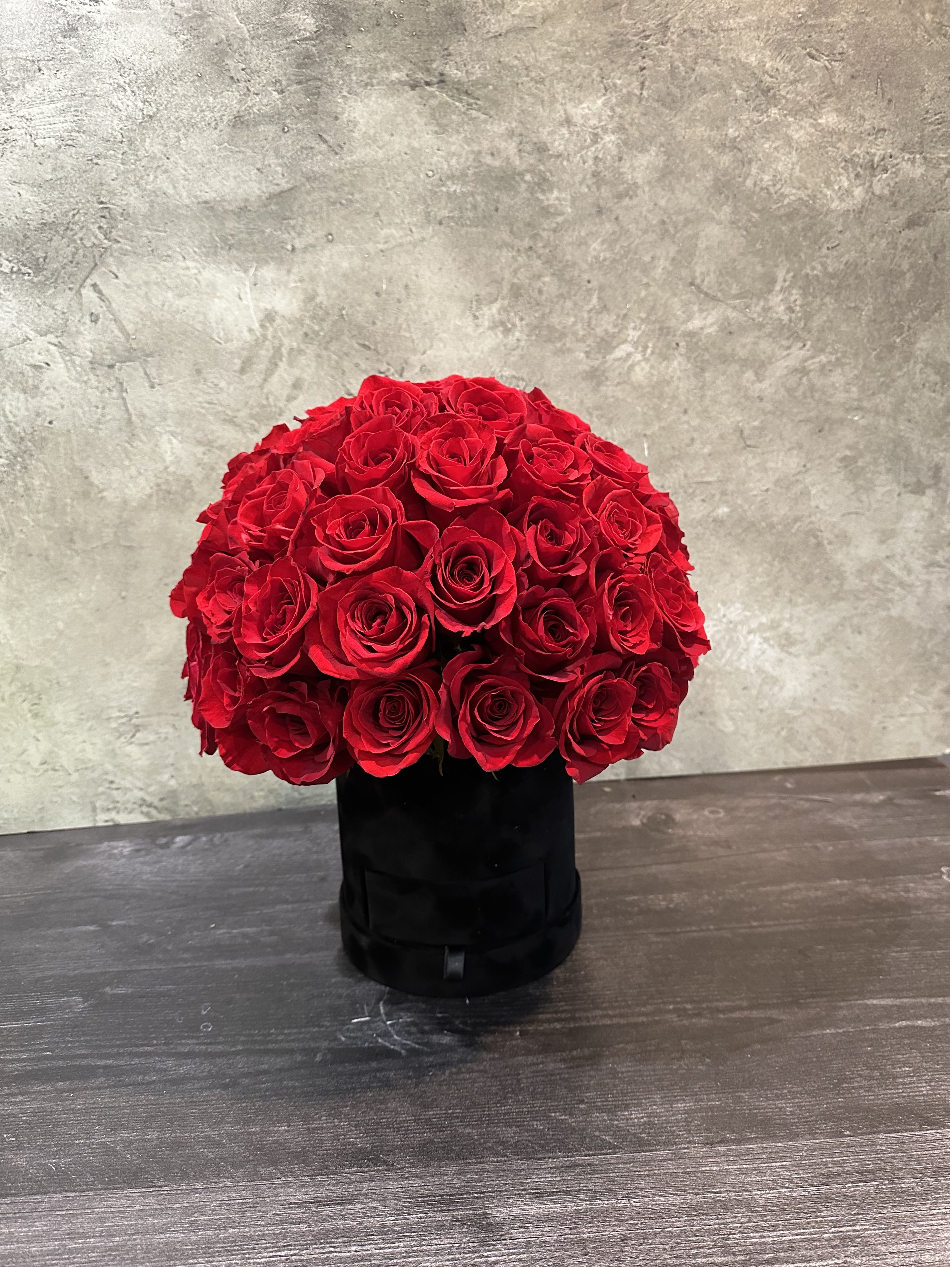 Round bouquet of red roses in a black box
