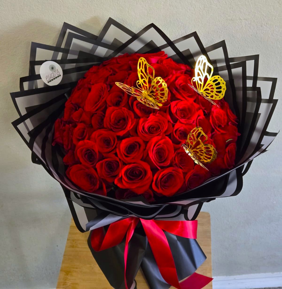 Bouquet of red roses wrapped in black paper with butterfly decorations