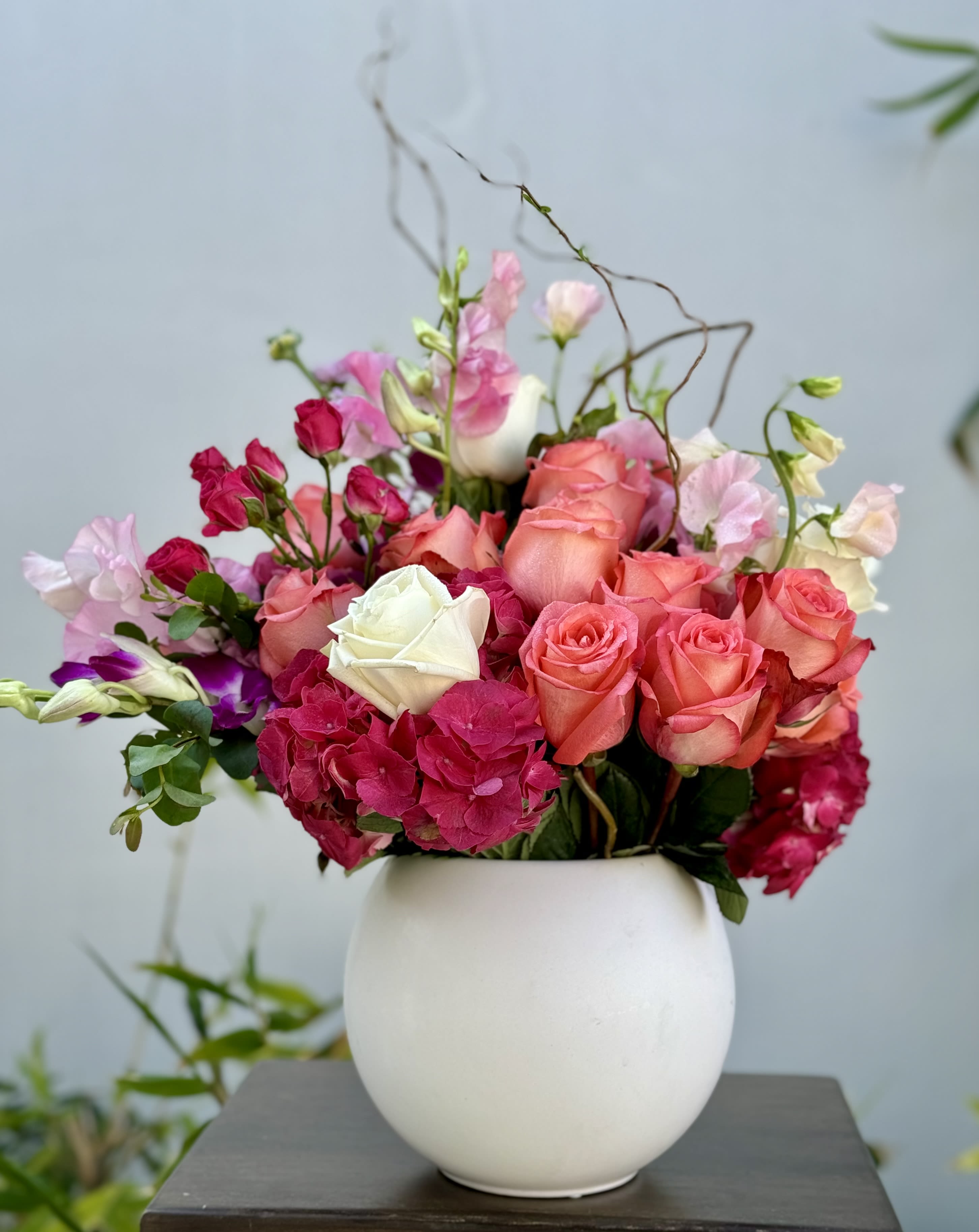 Pink and coral roses arranged in a white vase