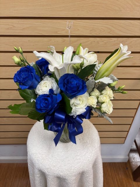 Blue and white bouquet with lilies and roses tied with a blue ribbon