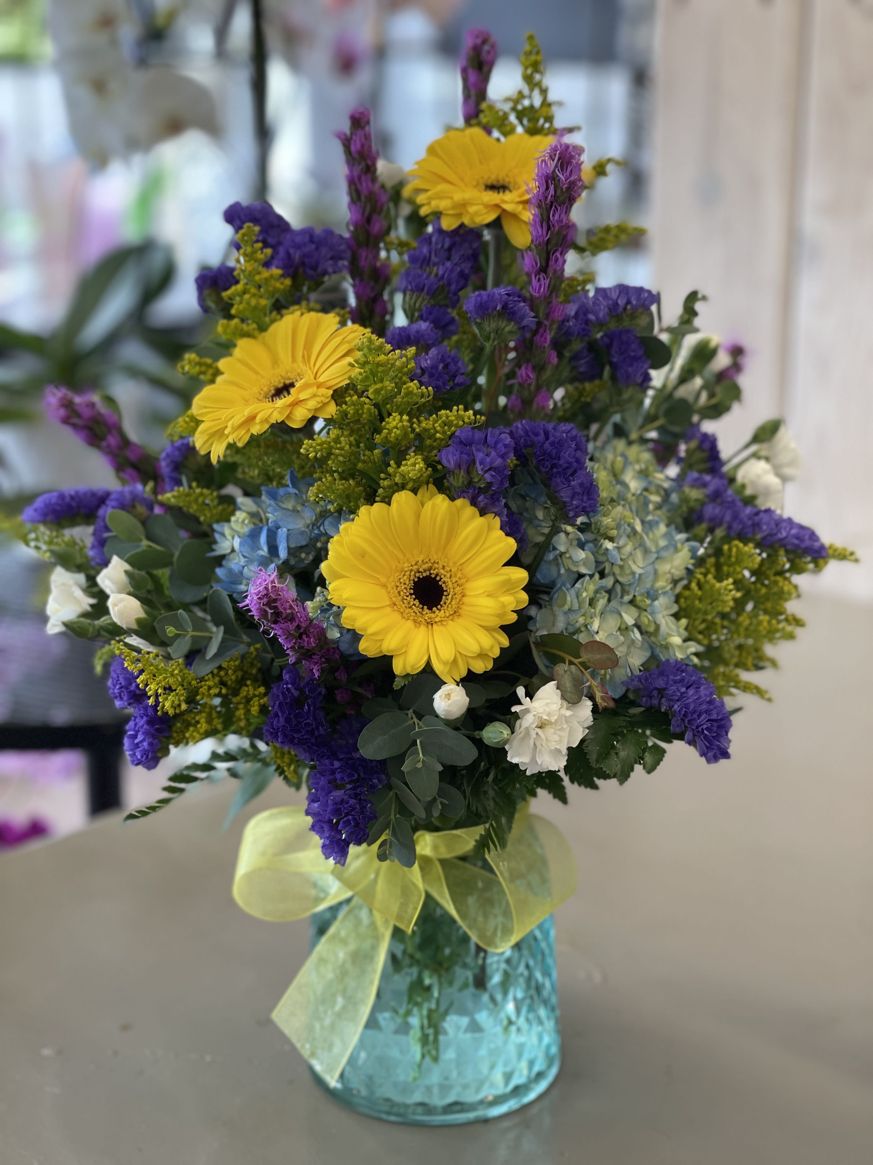 Bright mixed bouquet with yellow gerbera daisies in a blue vase