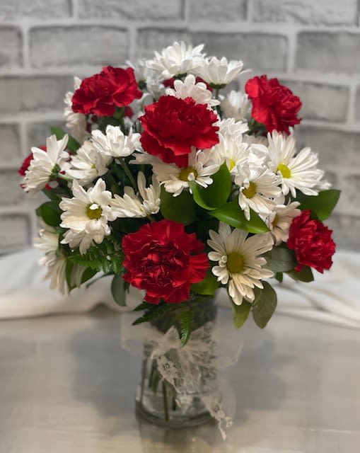 Bouquet of red carnations and white daisies in a glass vase