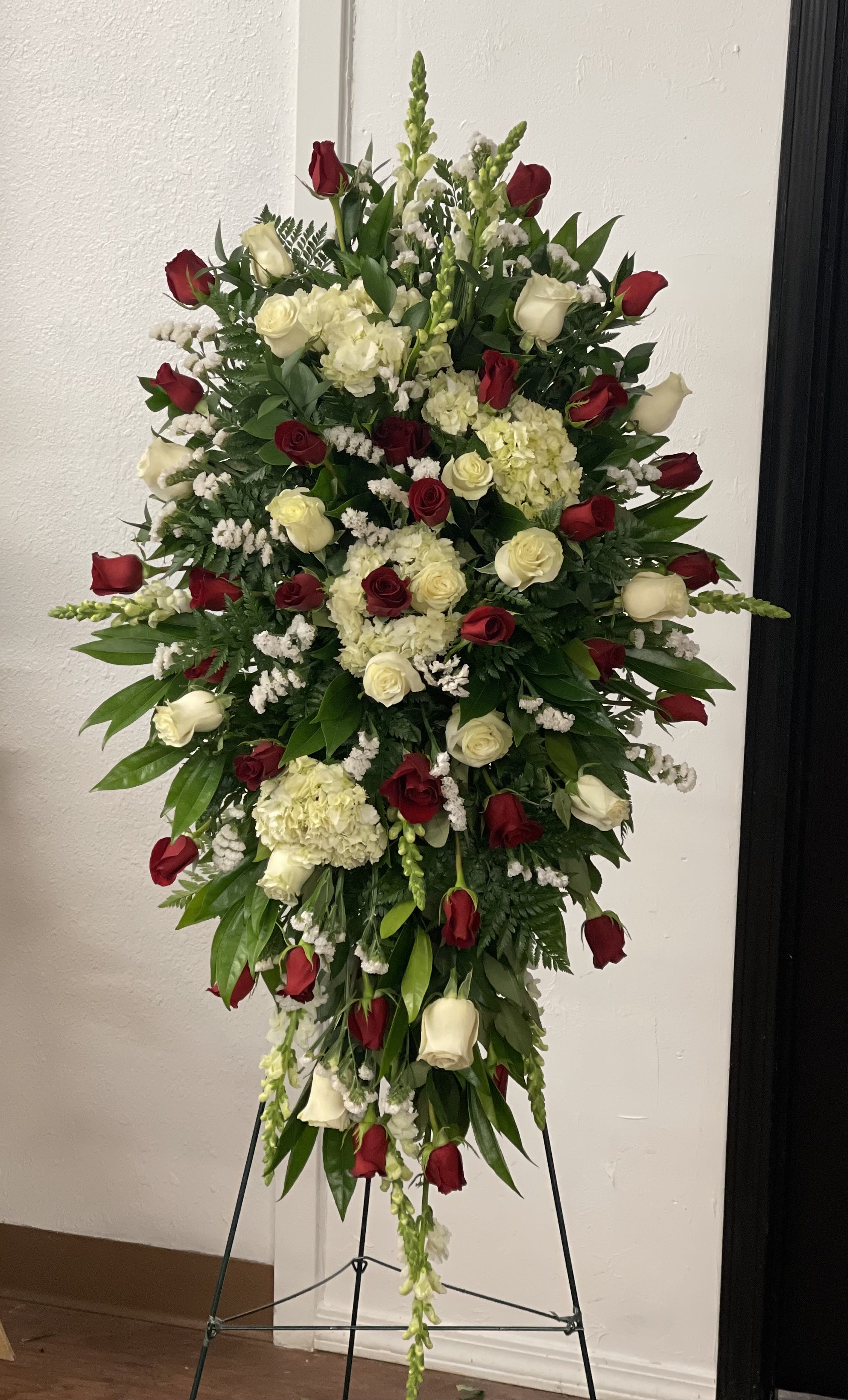 Tall standing floral spray with red and white roses and cream hydrangeas