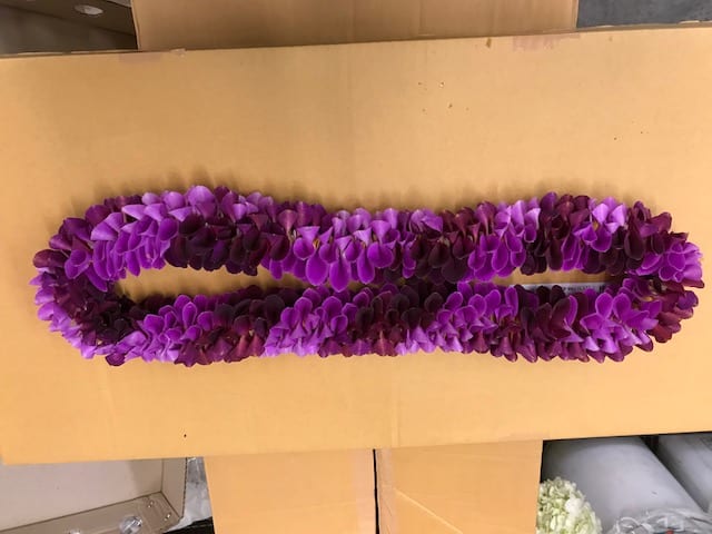 Purple flower lei on a cardboard surface