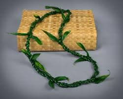Braided green vine garland draped over a woven straw clutch