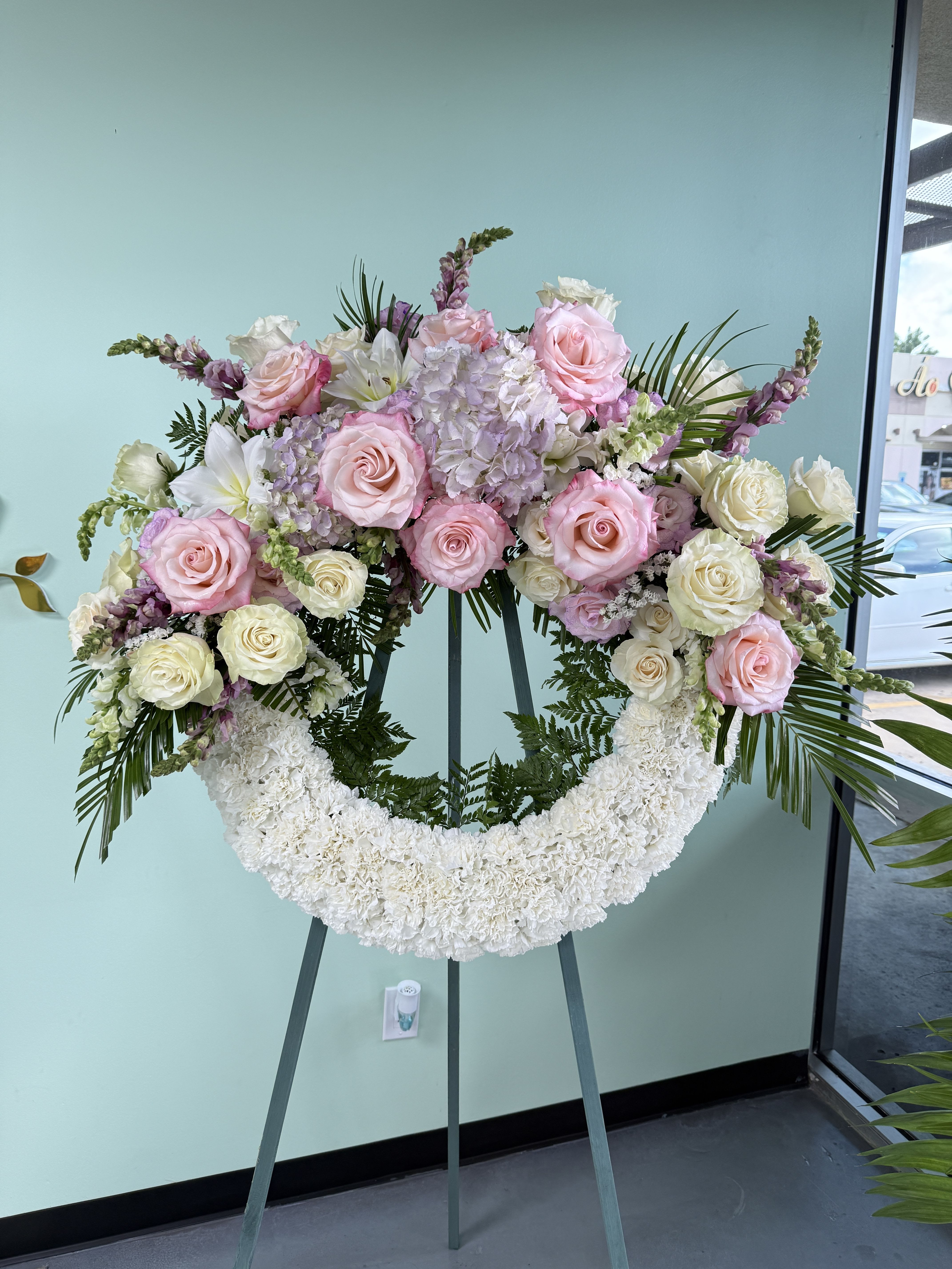 Sympathy Wreath Circle 02 - White, pink and lavender roses, hydrangeas, lilies and snapdragons form a soft, formal circular wreath on a metal easel-elegant and sympathetic for memorials or tribute displays.