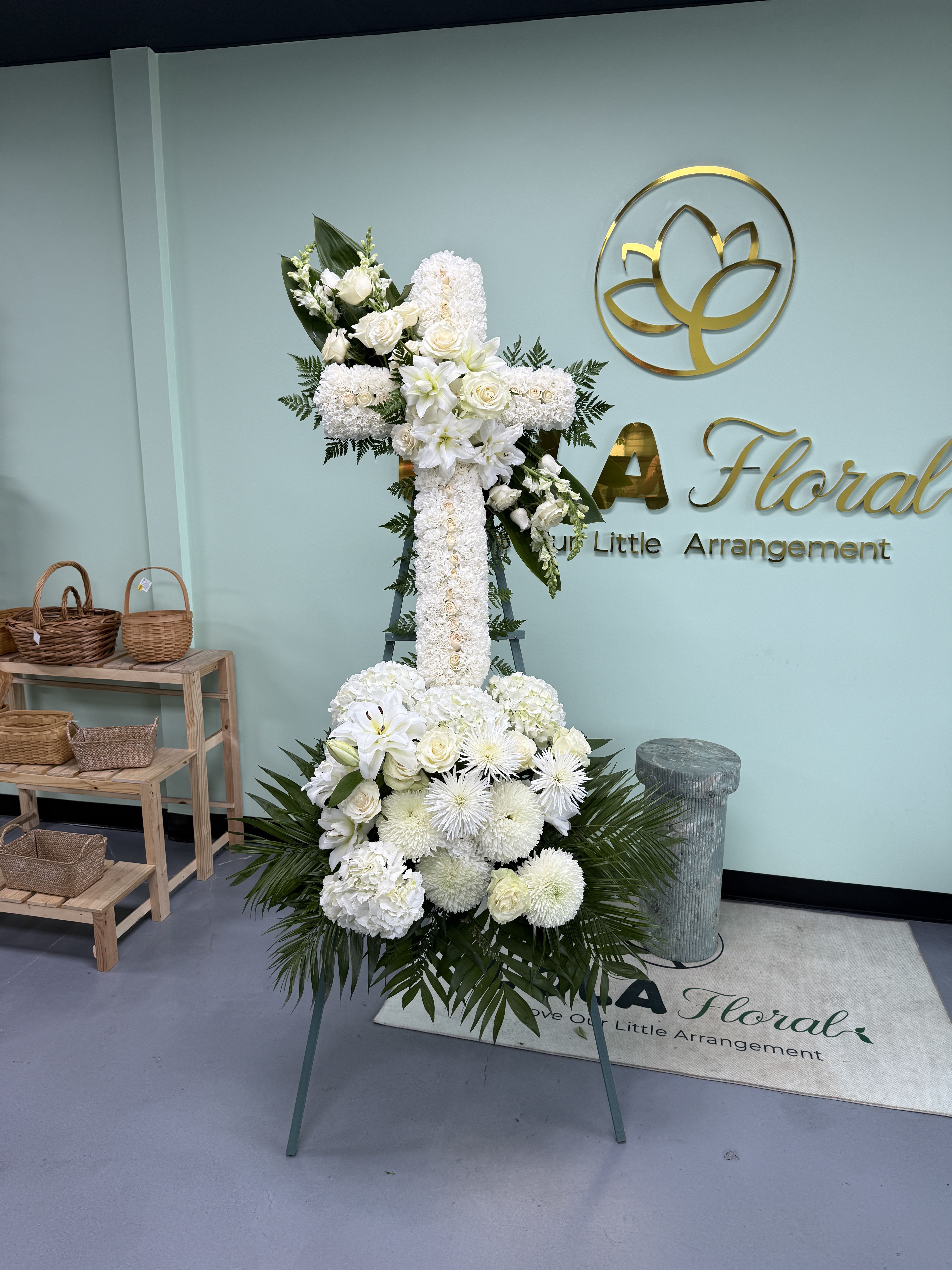 Sympathy Cross with Bundles - White sympathy cross of lilies, roses, chrysanthemums and hydrangea-like blooms with green foliage on an easel-formal, serene tribute for memorial services.