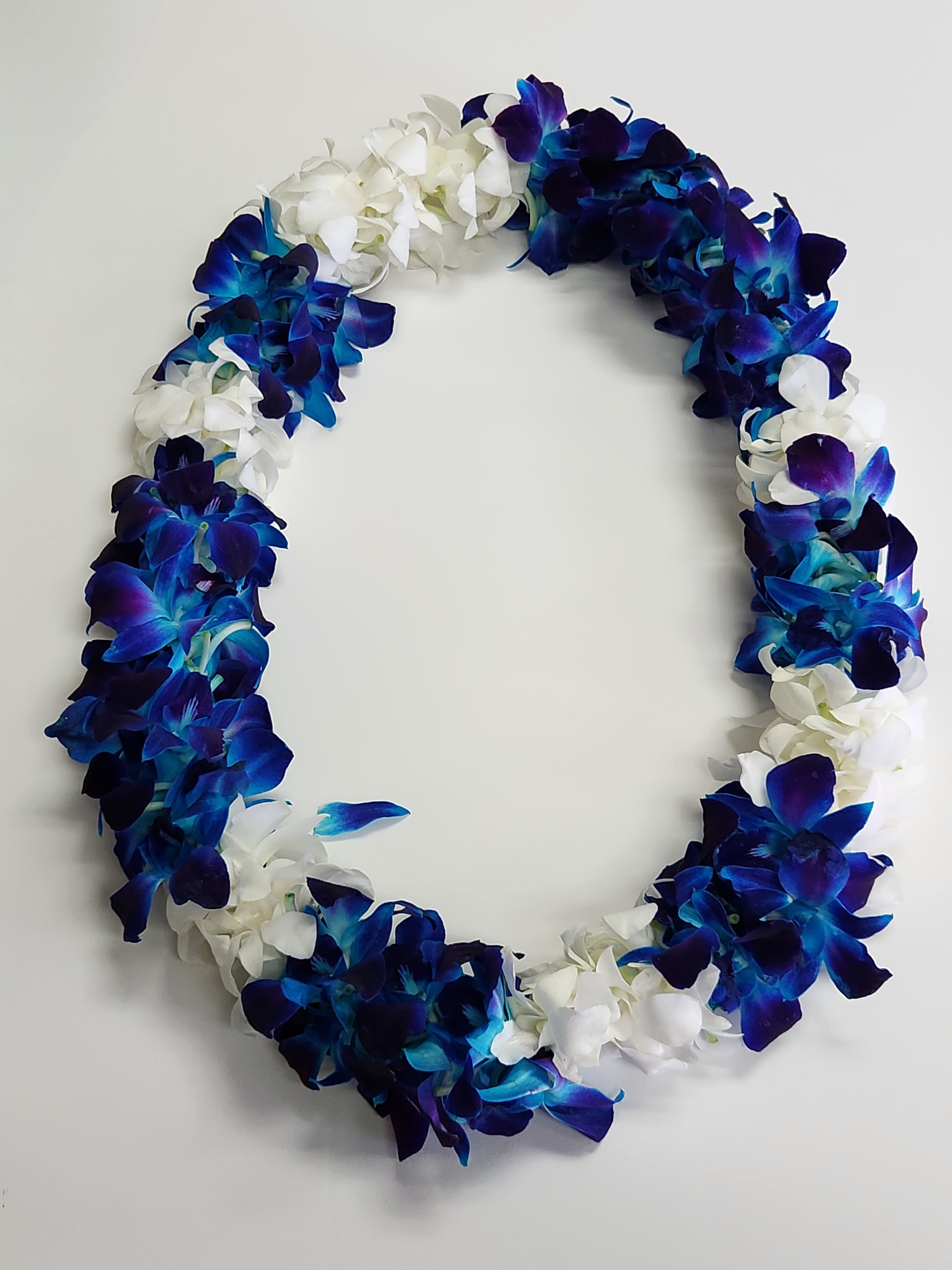 Lei of blue and purple orchids mixed with white blossoms in an oval shape