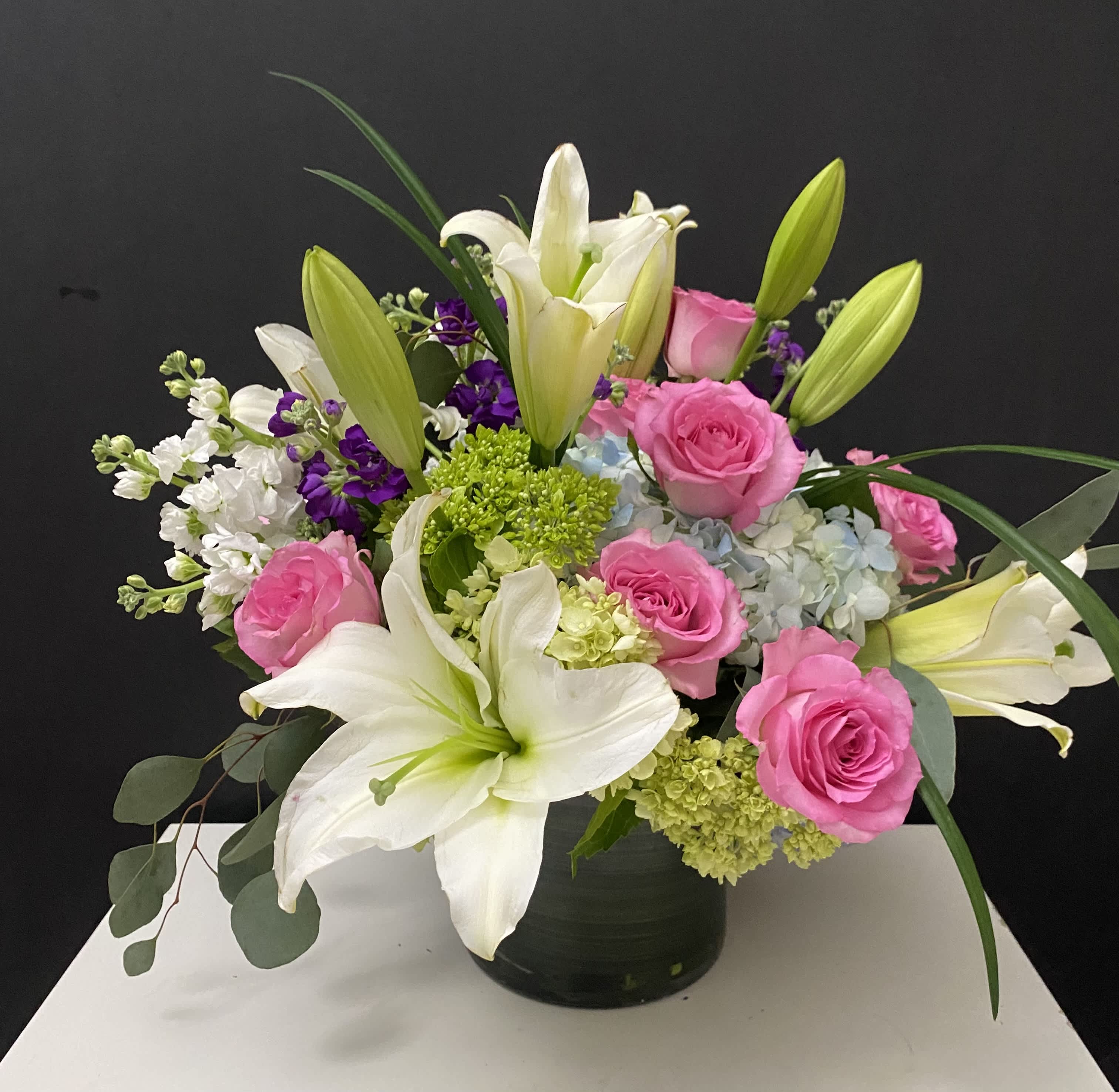 Pink roses and white lilies arranged in a black vase