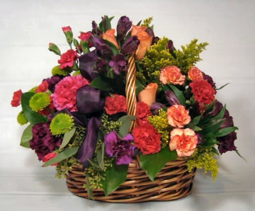 Basket arrangement of roses, carnations, and purple flowers