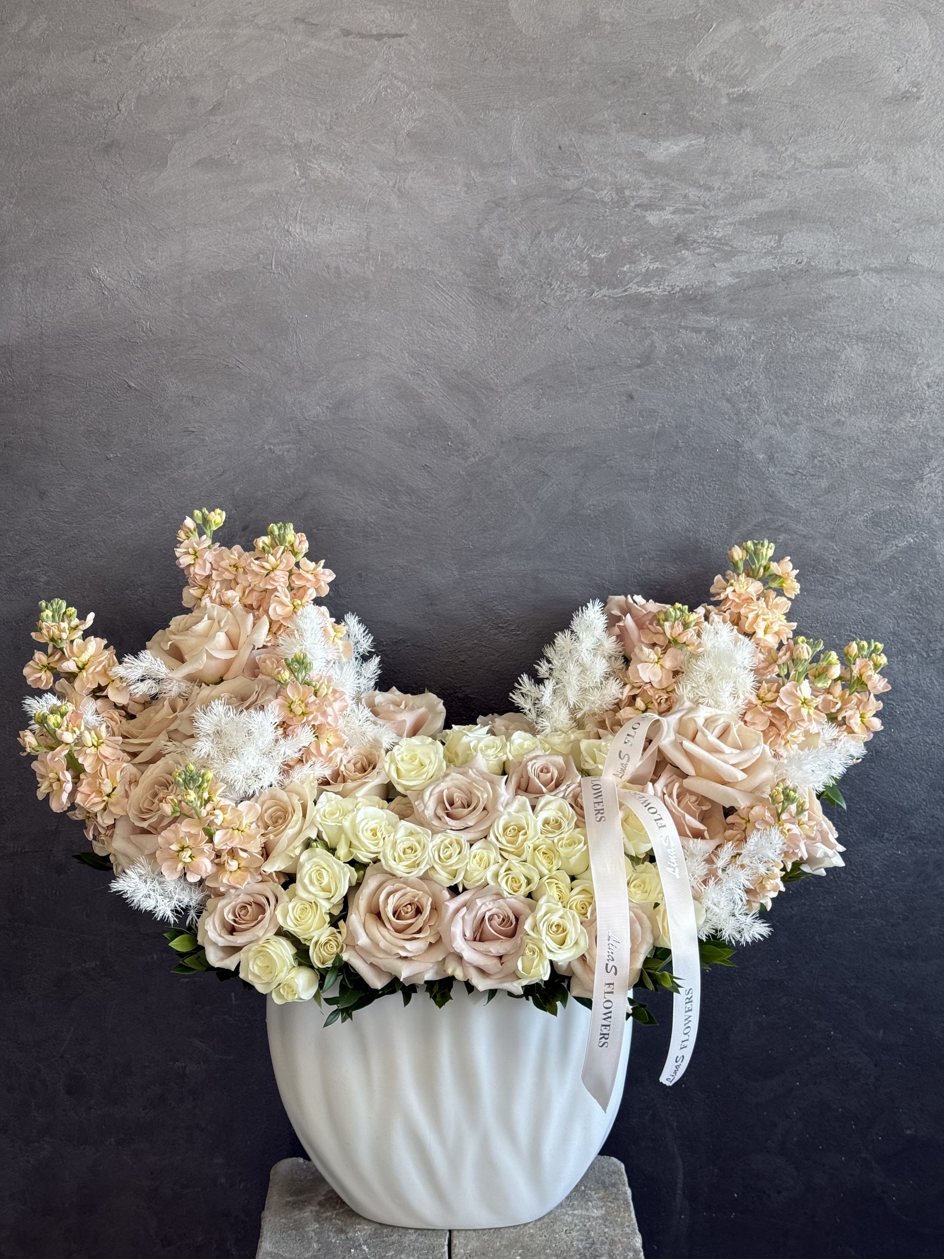 Aria blush  - A graceful arrangement featuring soft blush roses, delicate seasonal blooms, and lush greenery. Designed in romantic pastel tones, it brings elegance, warmth, and timeless beauty to any occasion. Perfect for celebrating life’s sweetest moments. 