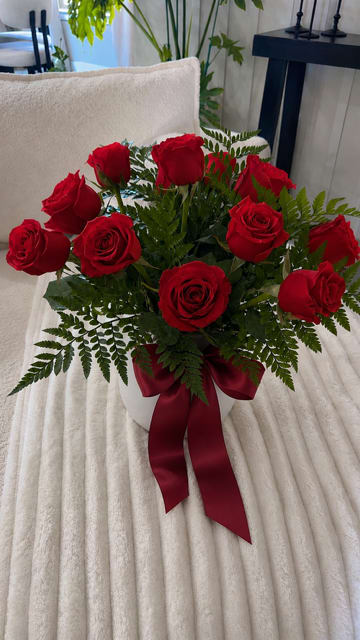 Classic 12  Red Rose vase - A classic and elegant arrangement of a dozen premium red roses in a clean white vase, beautifully finished with a rich burgundy satin bow. Perfect for anniversaries, birthdays, or just because. Flower delivery available in Midland, TX. Un elegante y clásico arreglo de una docena de rosas rojas premium en una base blanca, complementado con un hermoso moño de satén color vino. Ideal para aniversarios, cumpleaños o cualquier ocasión especial. Florería con servicio a domicilio en Midland, Texas.