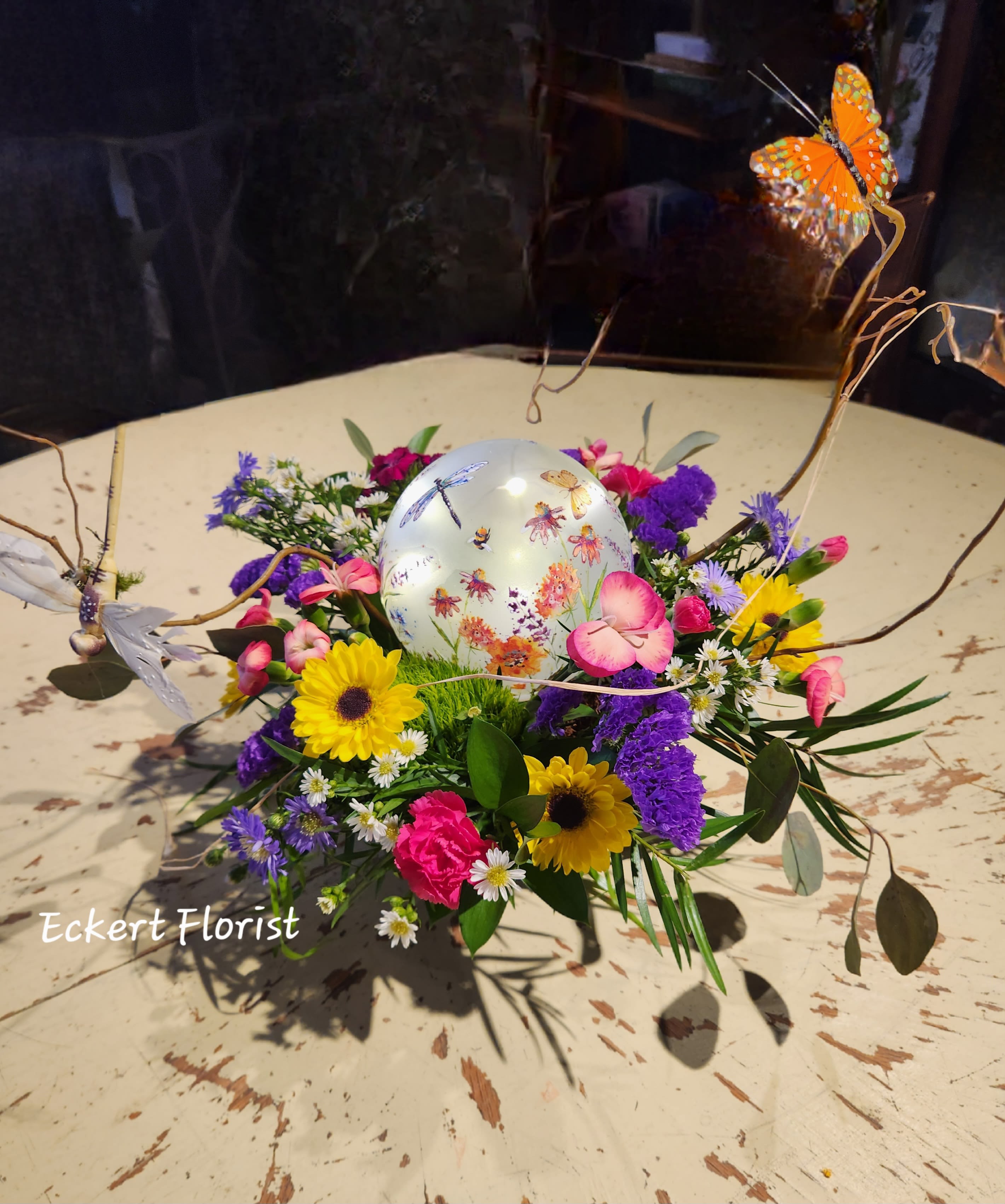 Eckert Florist's Garden Glow Bouquet - Featuring a LED lighted plastic garden themed globe (Batteries included), this fresh floral centerpiece is filled with flowers and colors of the season. Standard: (Pictured Shown) Small globe measures 4.75" Diameter Deluxe: Medium globe measures 6" Diameter Premium: Large globe measures 7" Diameter