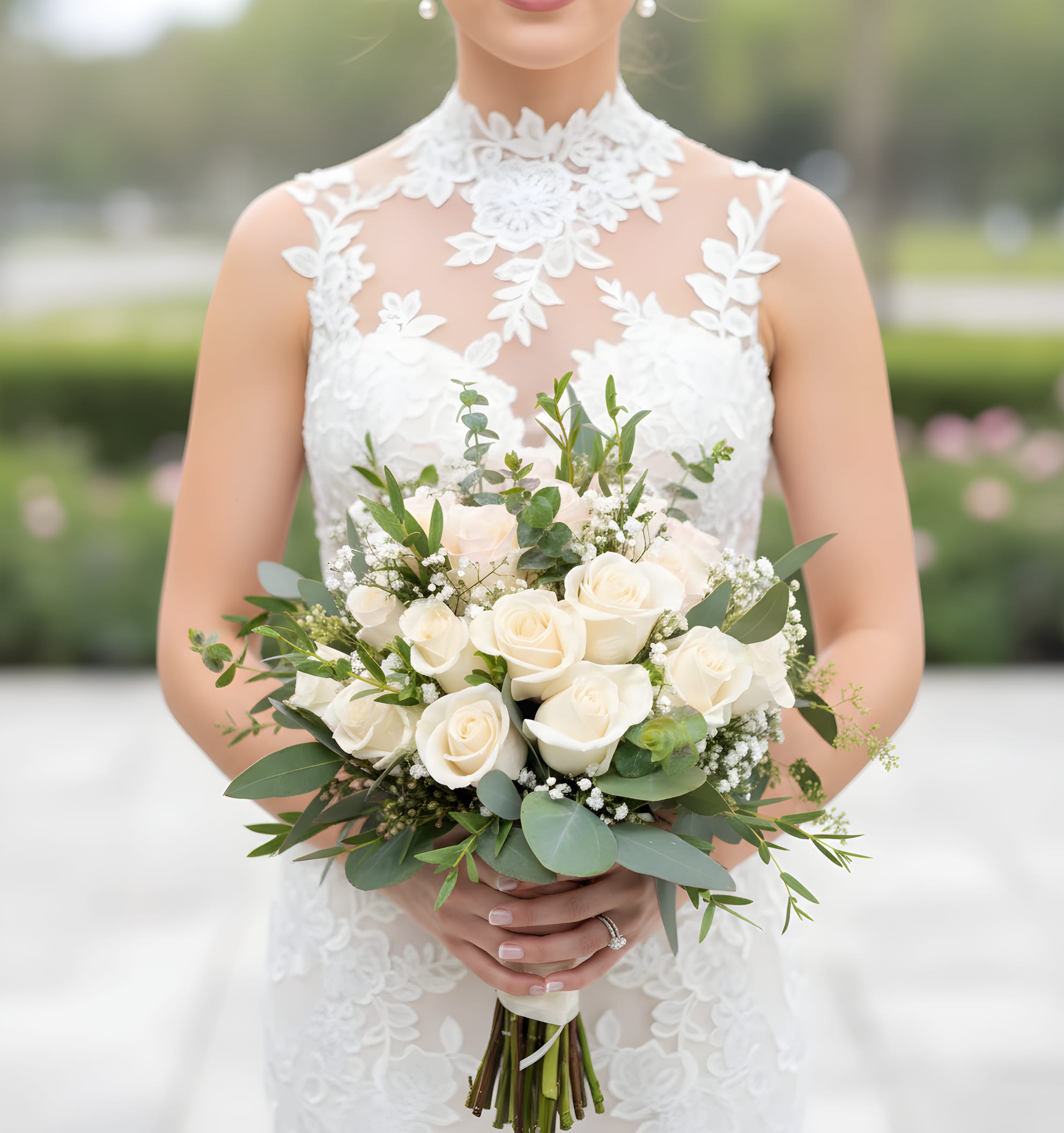 Bride holding a bouquet of white roses and greenery