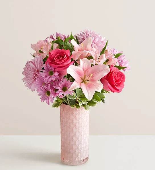 A Mothers Embrace - Thank Mom for a lifetime of comforting hugs with our Mother's Embrace™ Bouquet. Lovely pink and lavender blooms are hand-designed in a pink glass vase with subtle sparkle and pattern. This arrangement lets you express your feelings whether you're celebrating Mother’s Day together or sending a smile from miles away.