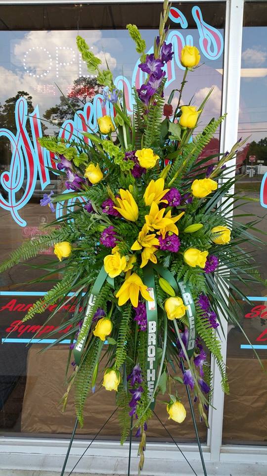 Tall standing floral spray with yellow roses and lilies, accented by purple flowers