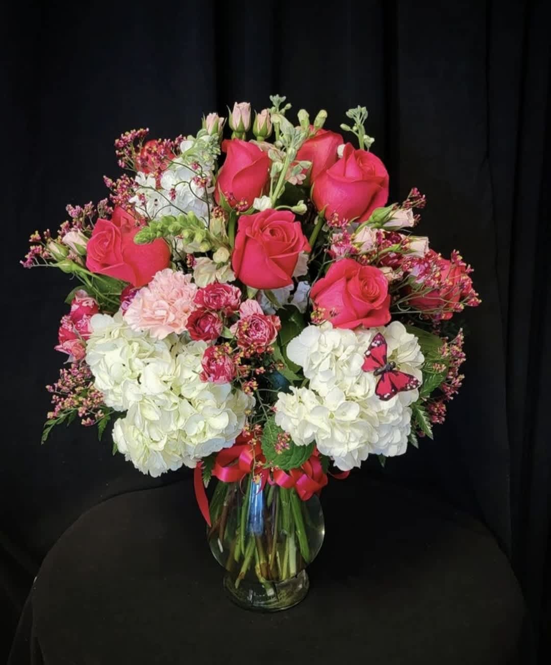 Pink roses and white hydrangeas in a glass vase with a ribbon