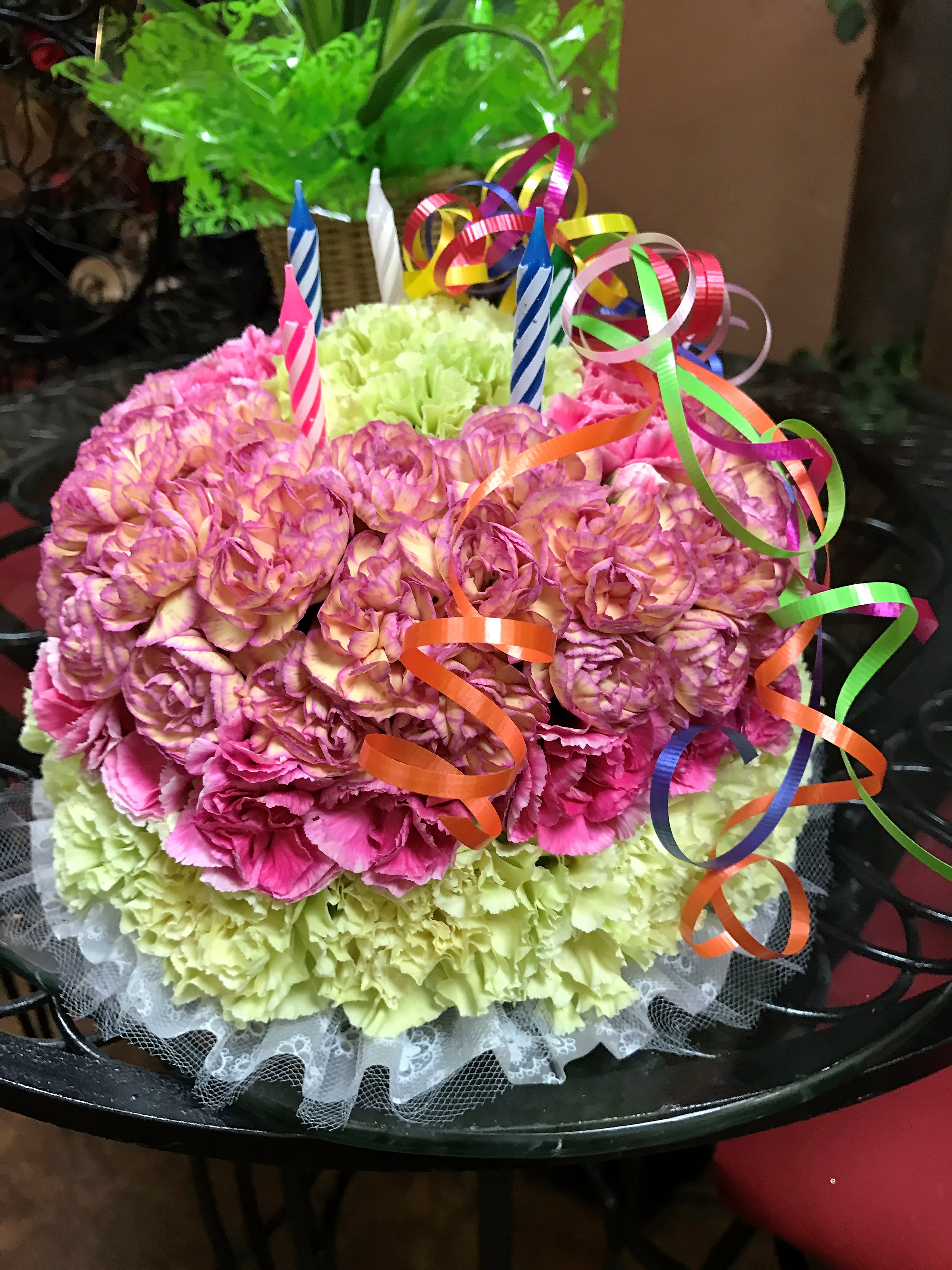 Round bouquet of pink and green carnations with ribbon curls and birthday candles