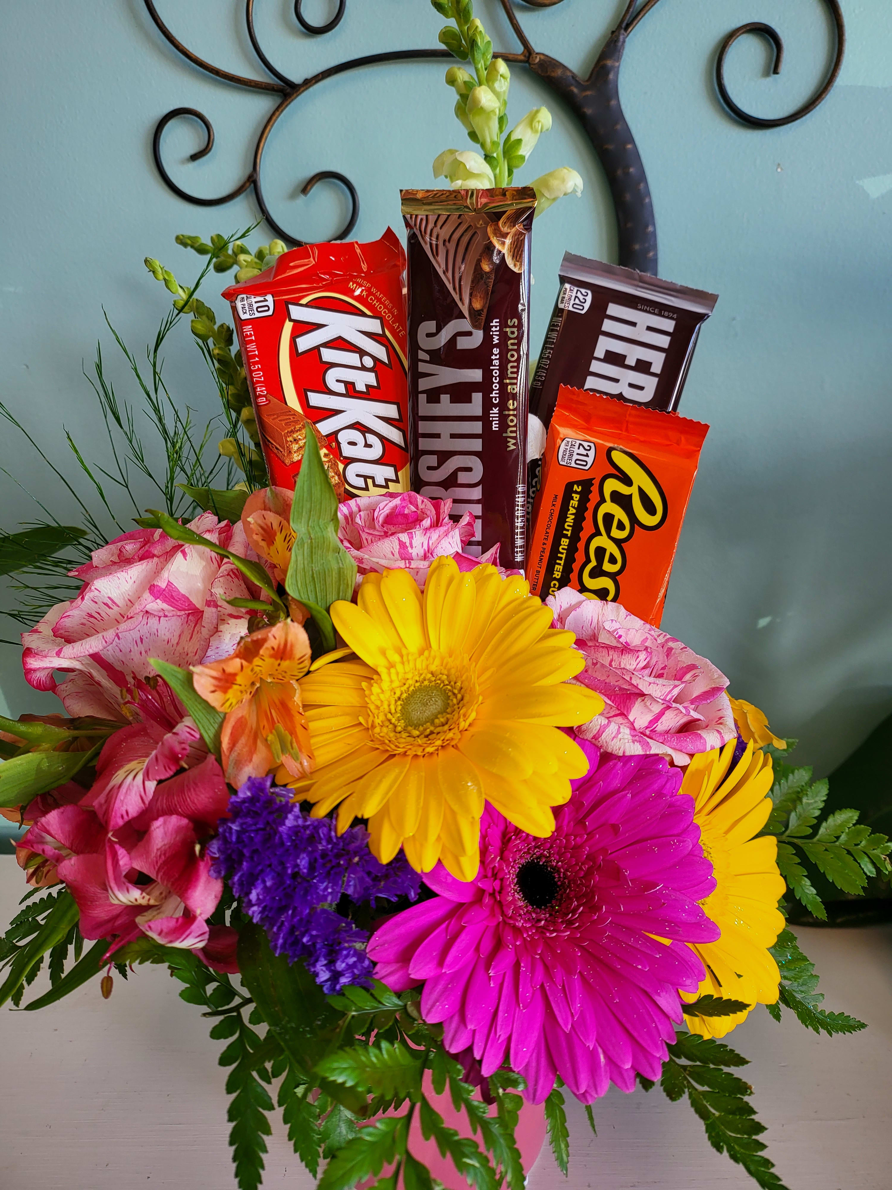Bouquet of bright flowers with candy bars arranged in the center