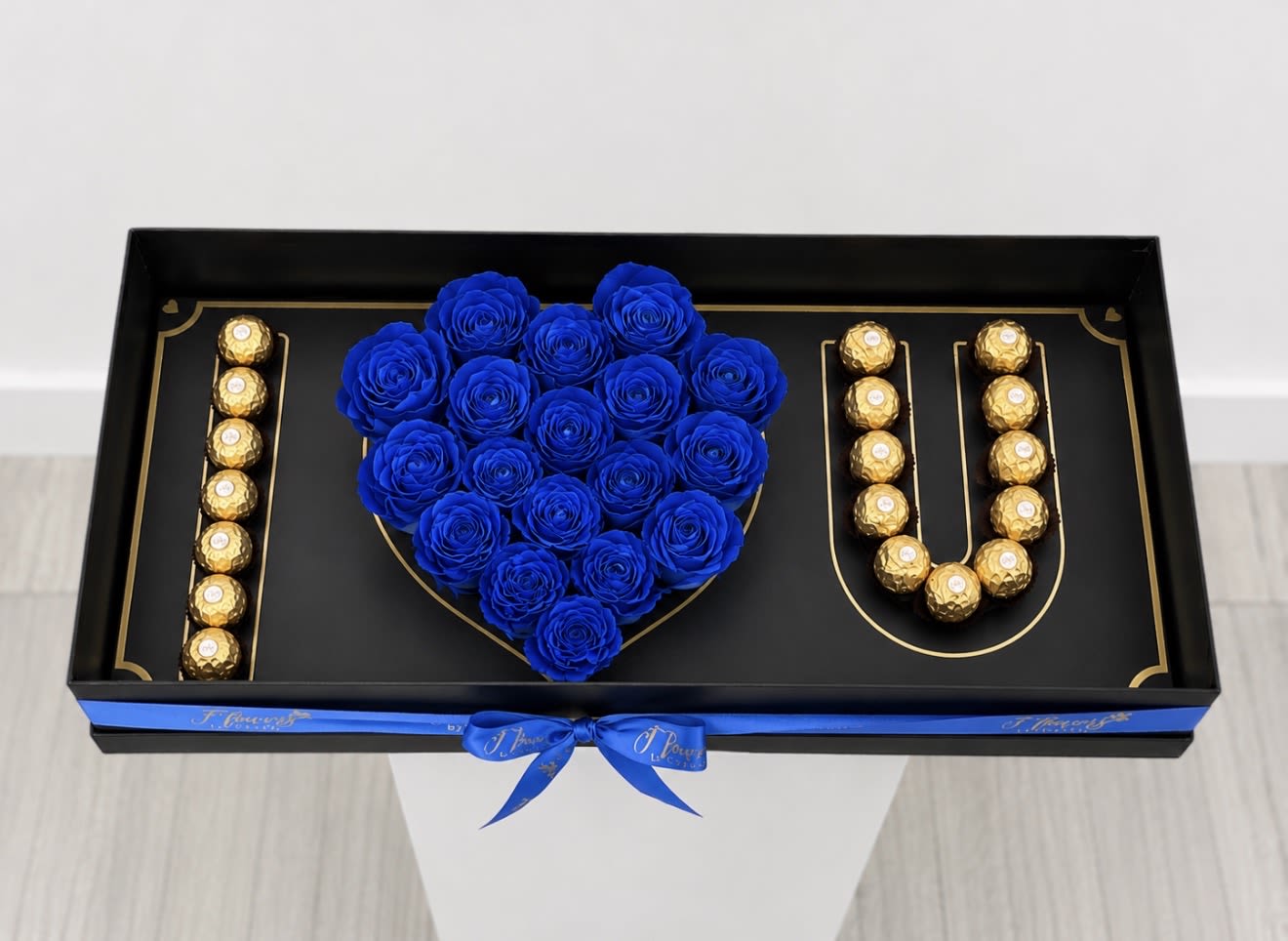 Midnight Blue Love Box - Express your love with our Royal Blue I ️ U Box, an elegant gift featuring a heart made of fresh blue roses and premium Ferrero Rocher chocolates arranged to spell "I ️ U". Presented in a luxurious black box with gold accents and finished with a royal blue satin ribbon, this unique creation is perfect for anniversaries, birthdays, Father's Day, Valentine's Day, or any special occasion.