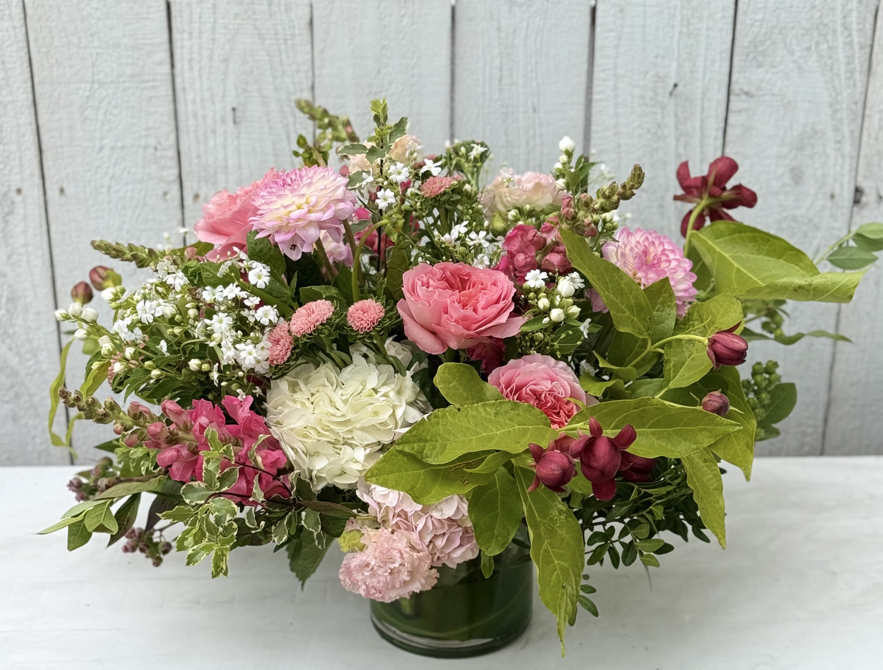 SAND DUNE FLORALS - Sand dune florals is a beautiful arrangement that is full of lovely garden roses, dahlias, lisianthus, hydrangeas, gorgeous summer blooming branches and amazing greenery. It comes designed in a 8x6 leaf lined container.