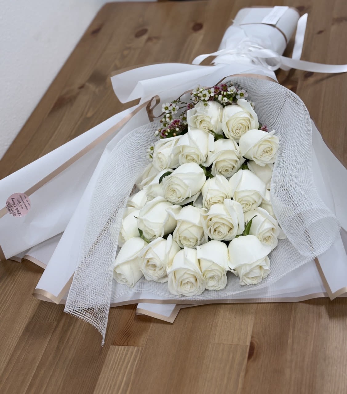 Bouquet of white roses wrapped in white mesh and paper