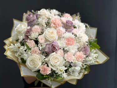 Bouquet of white, blush, and lavender roses with small white flowers