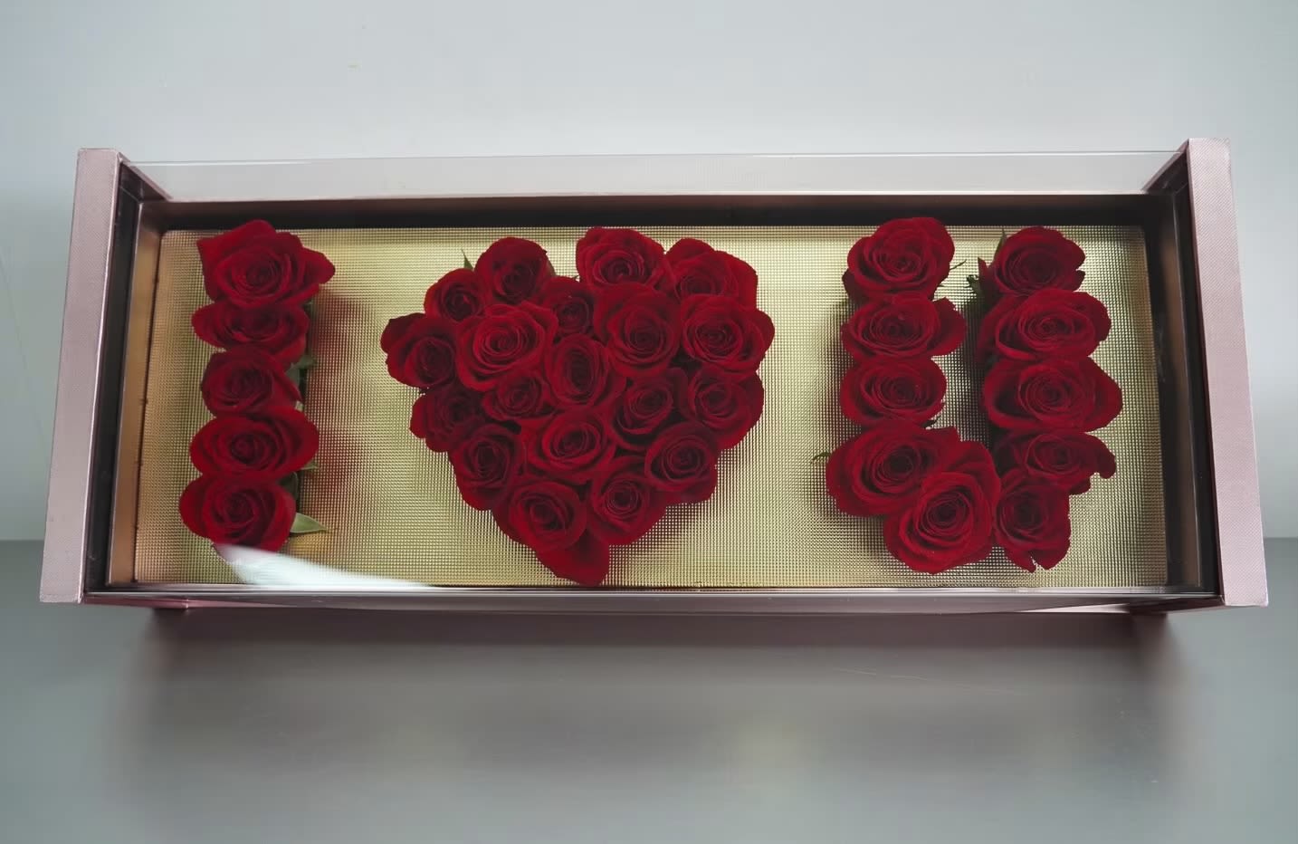 Red roses arranged in a rectangular display box spelling "I ♥ U"