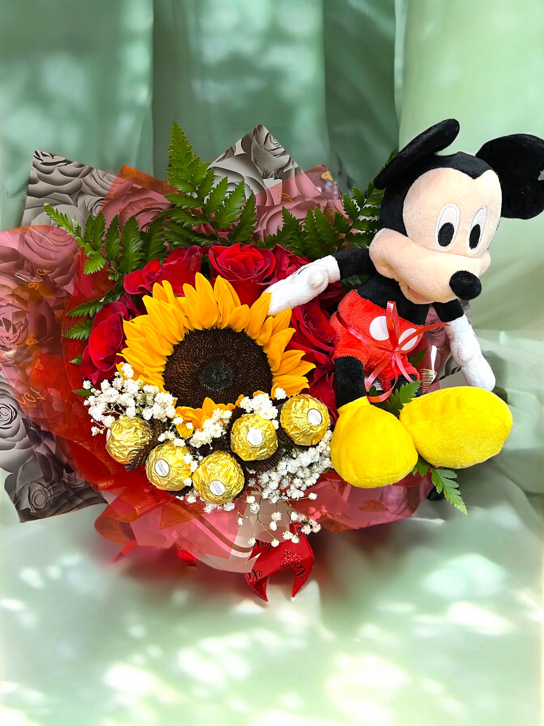Bouquet of red roses, a sunflower, chocolates, and a Mickey Mouse plush