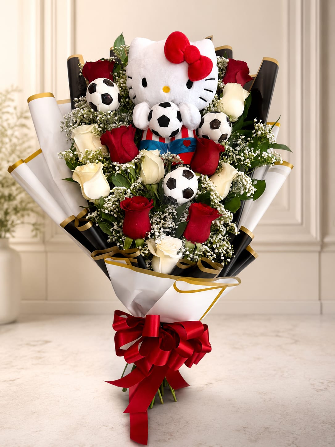 Hello Kitty MVP Bouquet  - Score big with a gift that’s as sweet as it is unforgettable! This playful bouquet features a lovable Hello Kitty plush surrounded by a beautiful mix of red and white roses, delicate baby’s breath, fresh greenery, and fun soccer accents. Wrapped in elegant black and white paper with gold details and finished with a bold red bow, this design is perfect for soccer fans, birthdays, graduations, celebrations, or anyone who loves Hello Kitty.